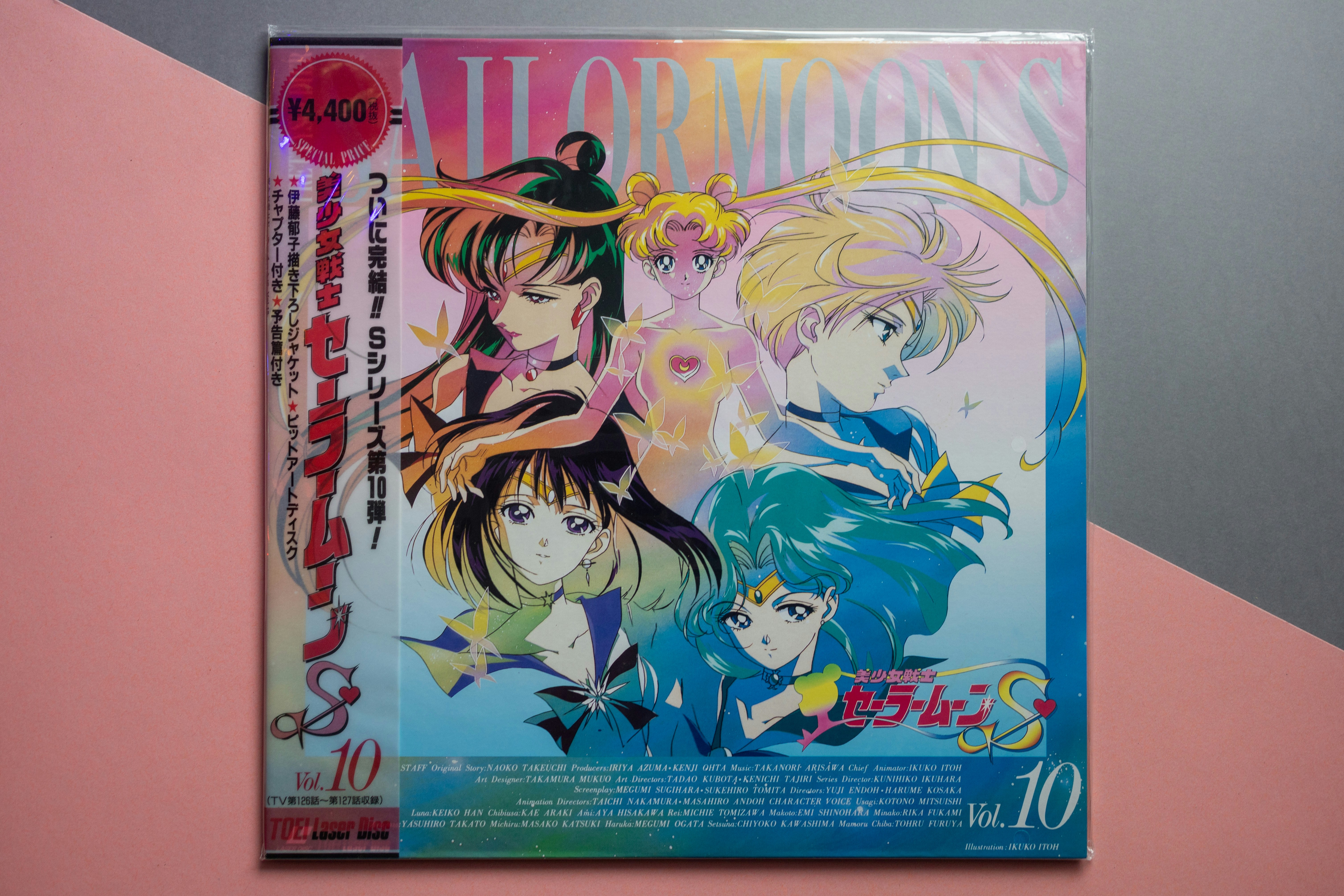 Personagens de anime em uma capa de laserdisc Sailor Moon S com degradés rosa e azul