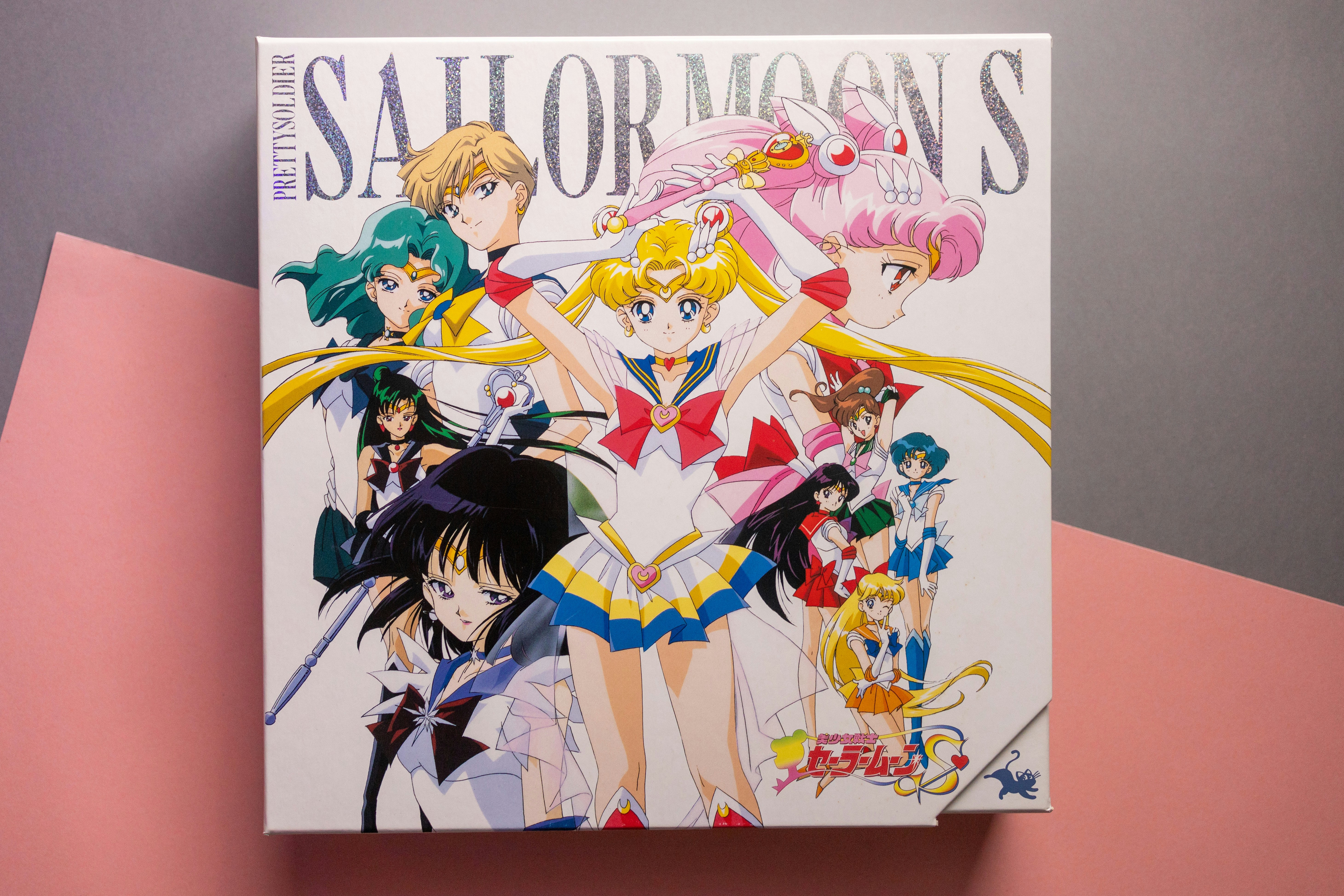 Uma caixa com personagens de Sailor Moon em estilo anime colorido sobre fundo branco