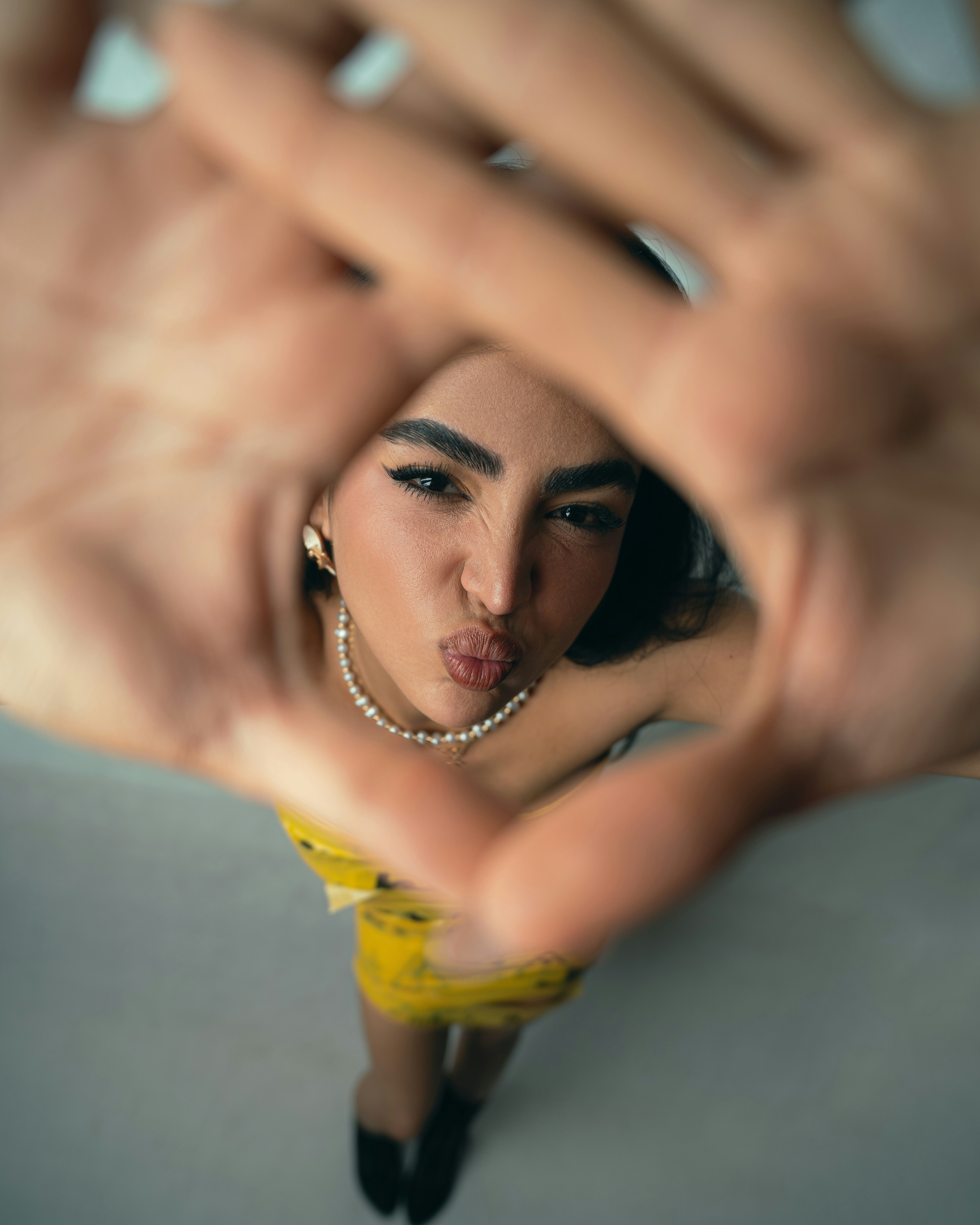 A woman in a yellow dress making a heart shape with her hands
