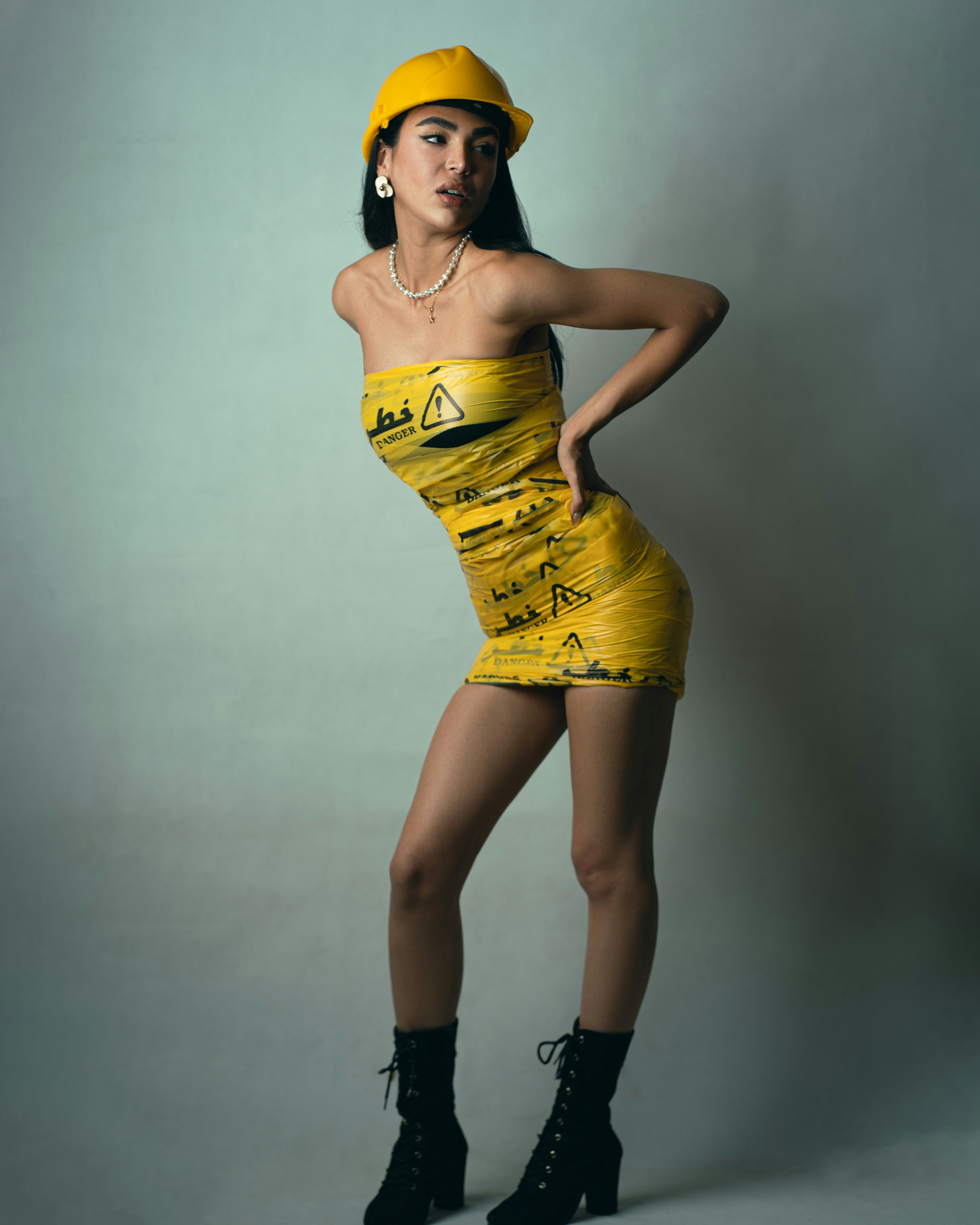 A woman wearing a yellow hard hat and a dress made of danger tape