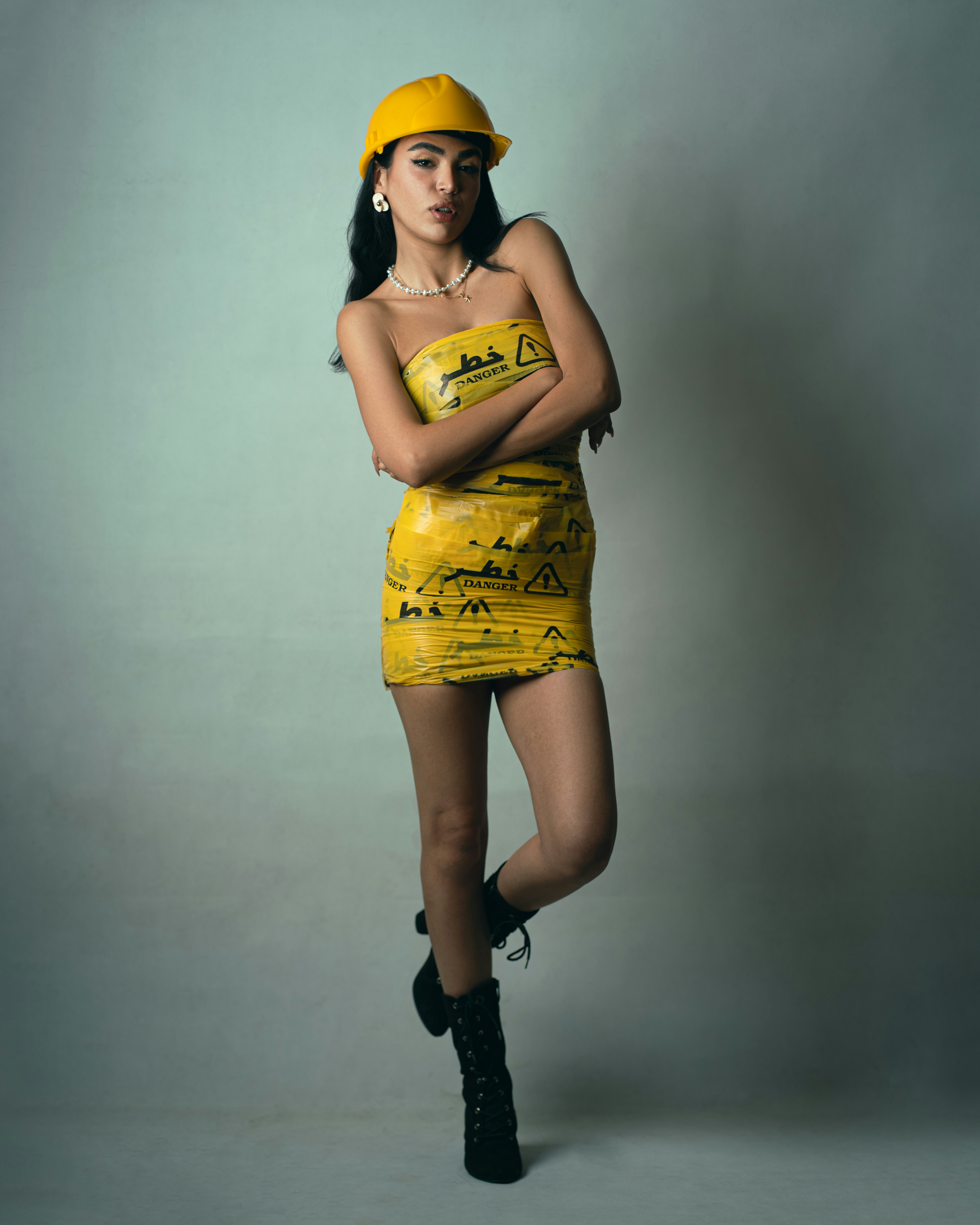 A woman wearing a yellow hard hat and a dress made of yellow danger tape