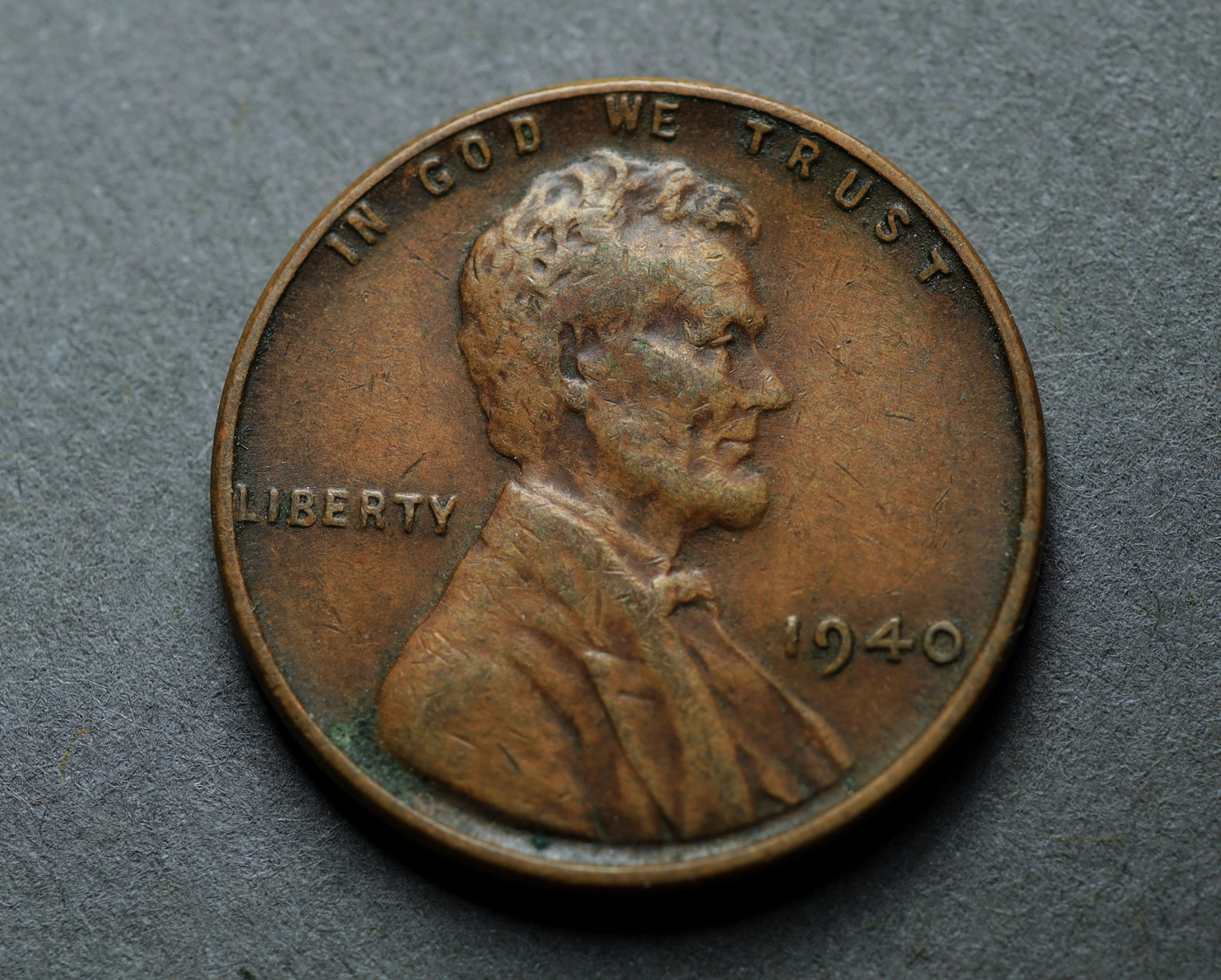 A 1940 United States penny with Abraham Lincoln in profile on a grey surface
