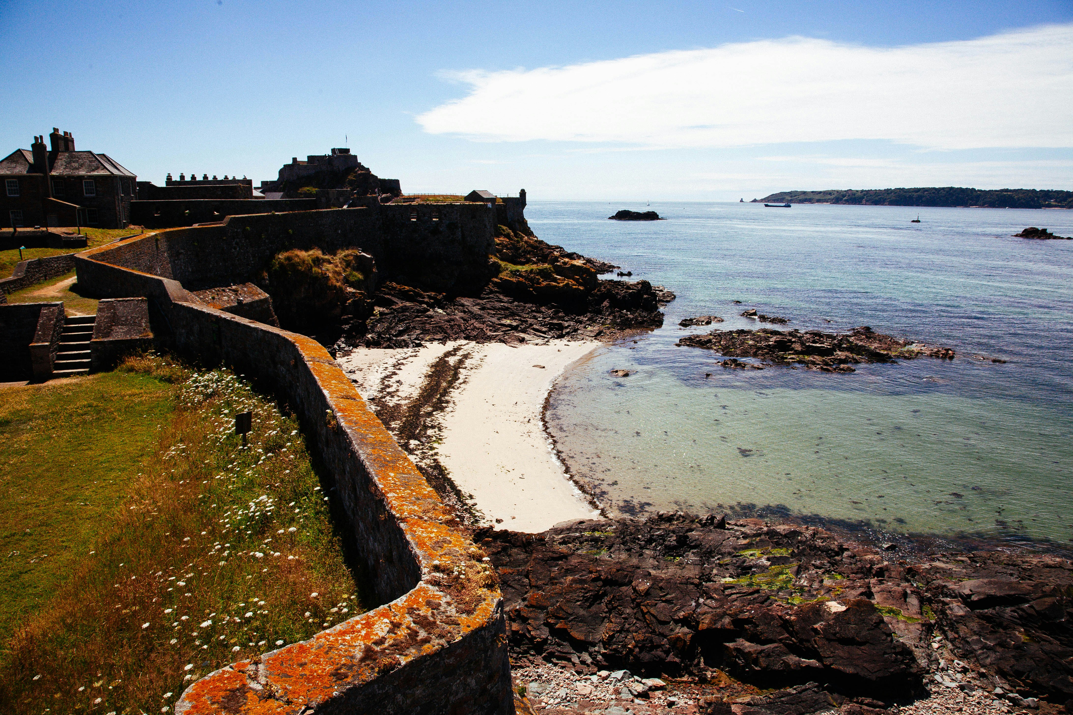 A stone fortress overlooking a sandy beach and the blue sea