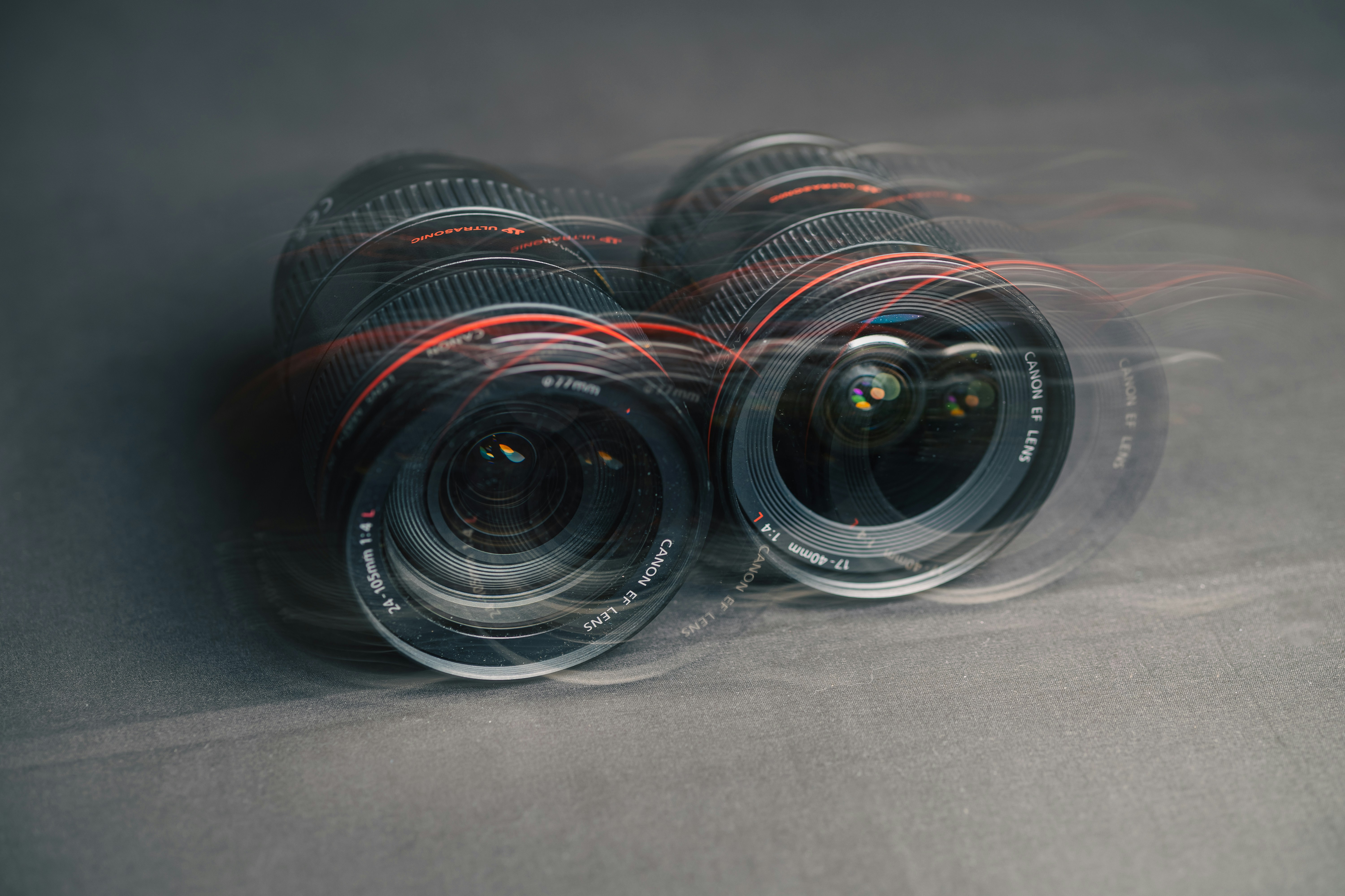 Two camera lenses with motion blur on a dark grey surface