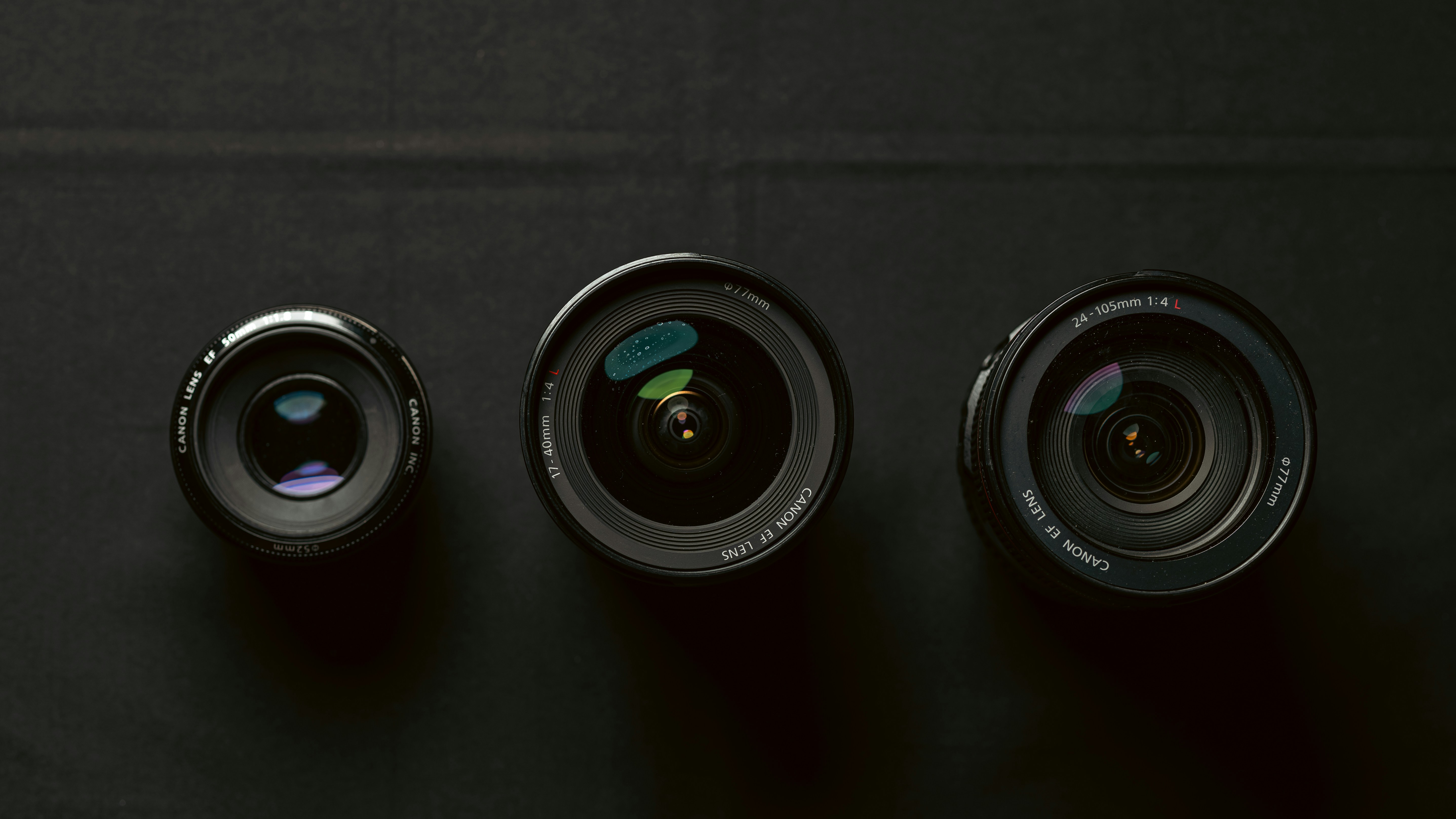 Three camera lenses arranged in a row on a dark textured surface