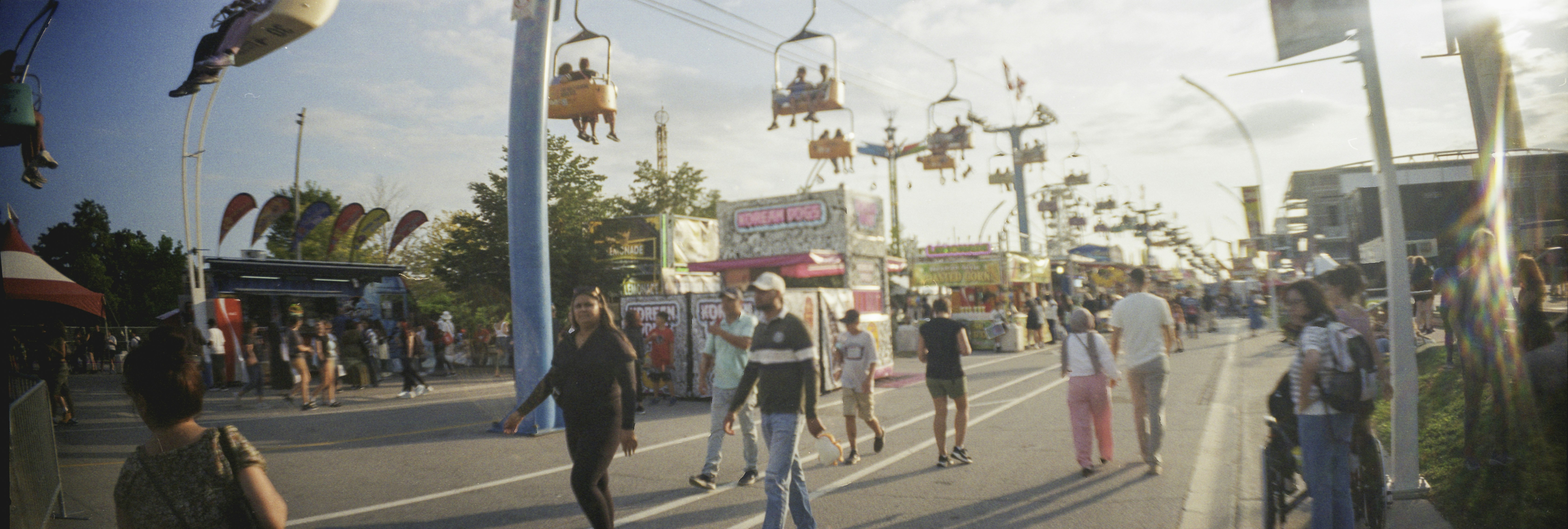 People walking along a path at a fair with overhead chairlift rides