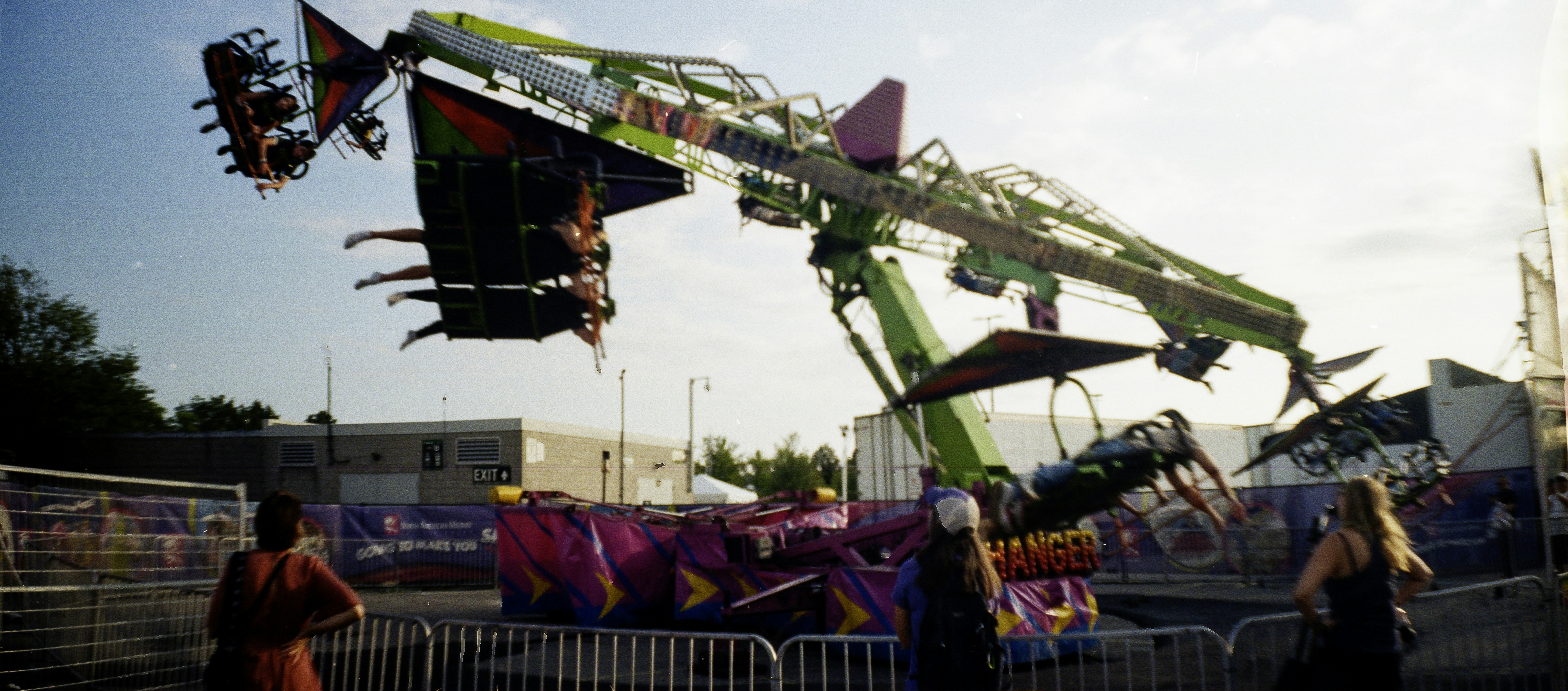 People riding a spinning carnival attraction with a bright green mechanical arm