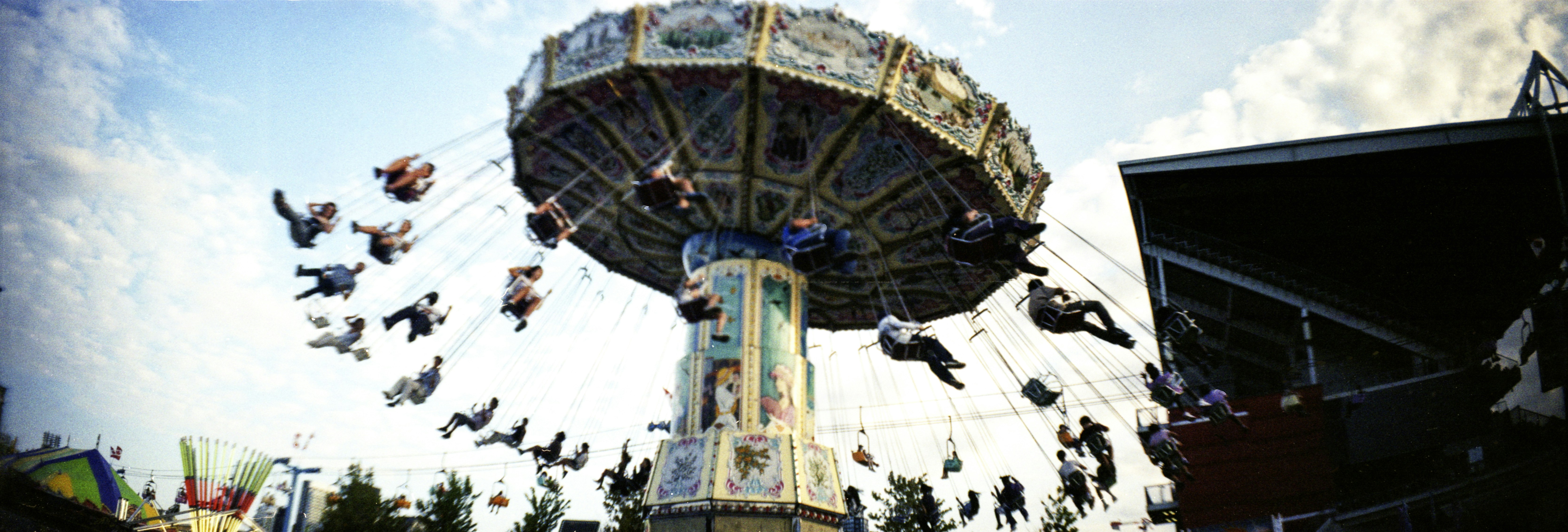 People riding a spinning swing carousel at an amusement park under a blue sky