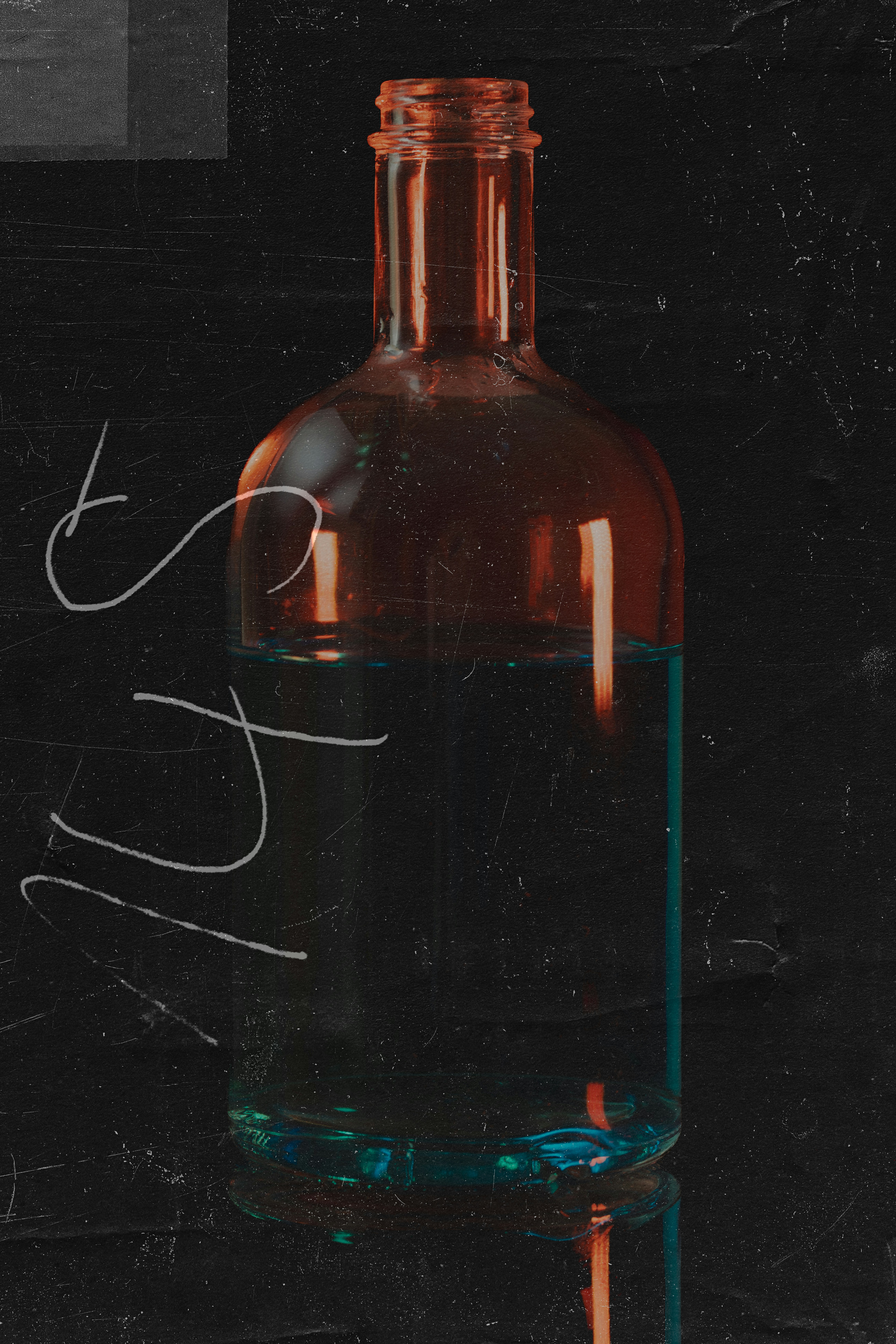 A glass bottle filled with blue liquid against a dark textured background