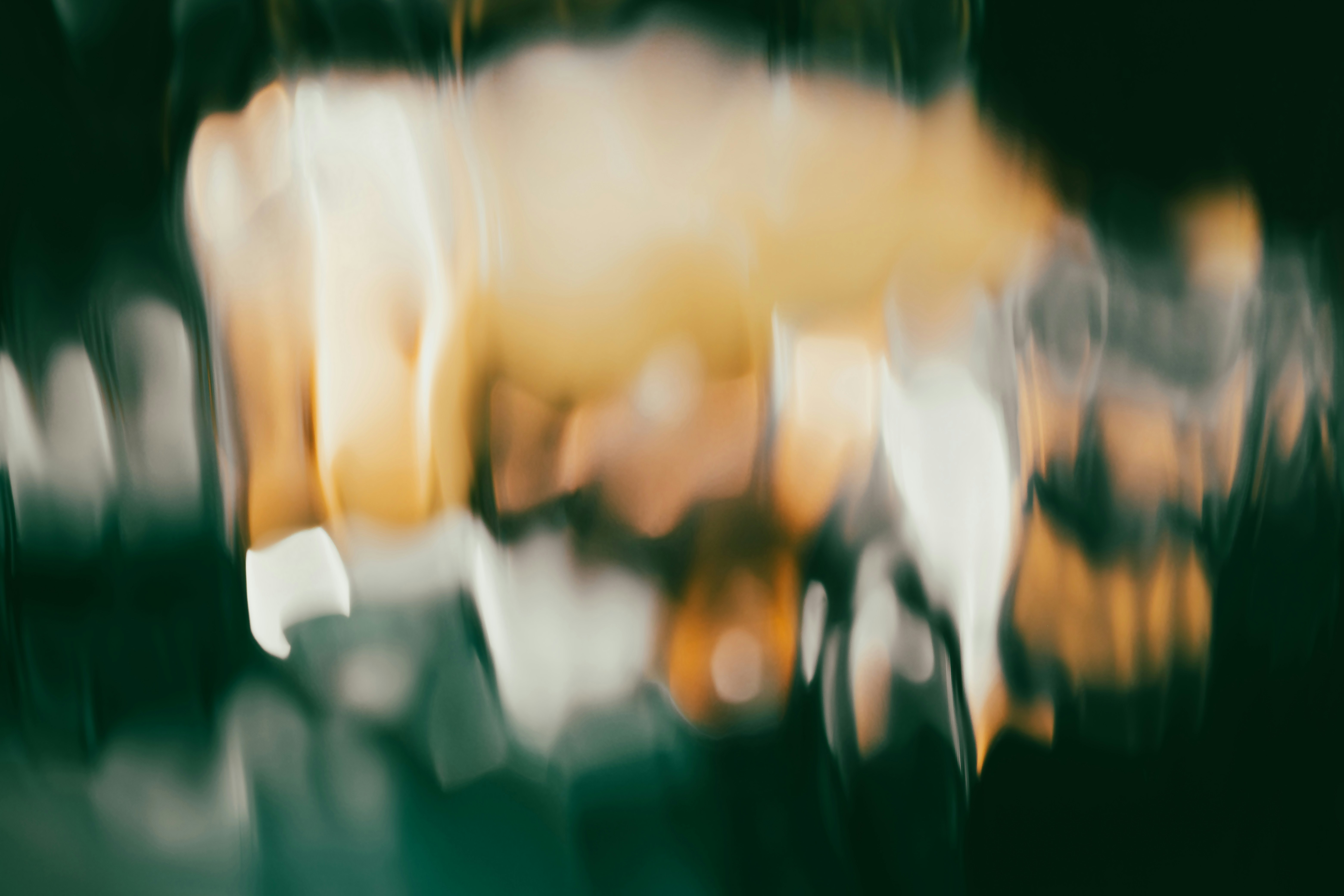 Abstract blurred shapes in shades of gold, white, and dark green