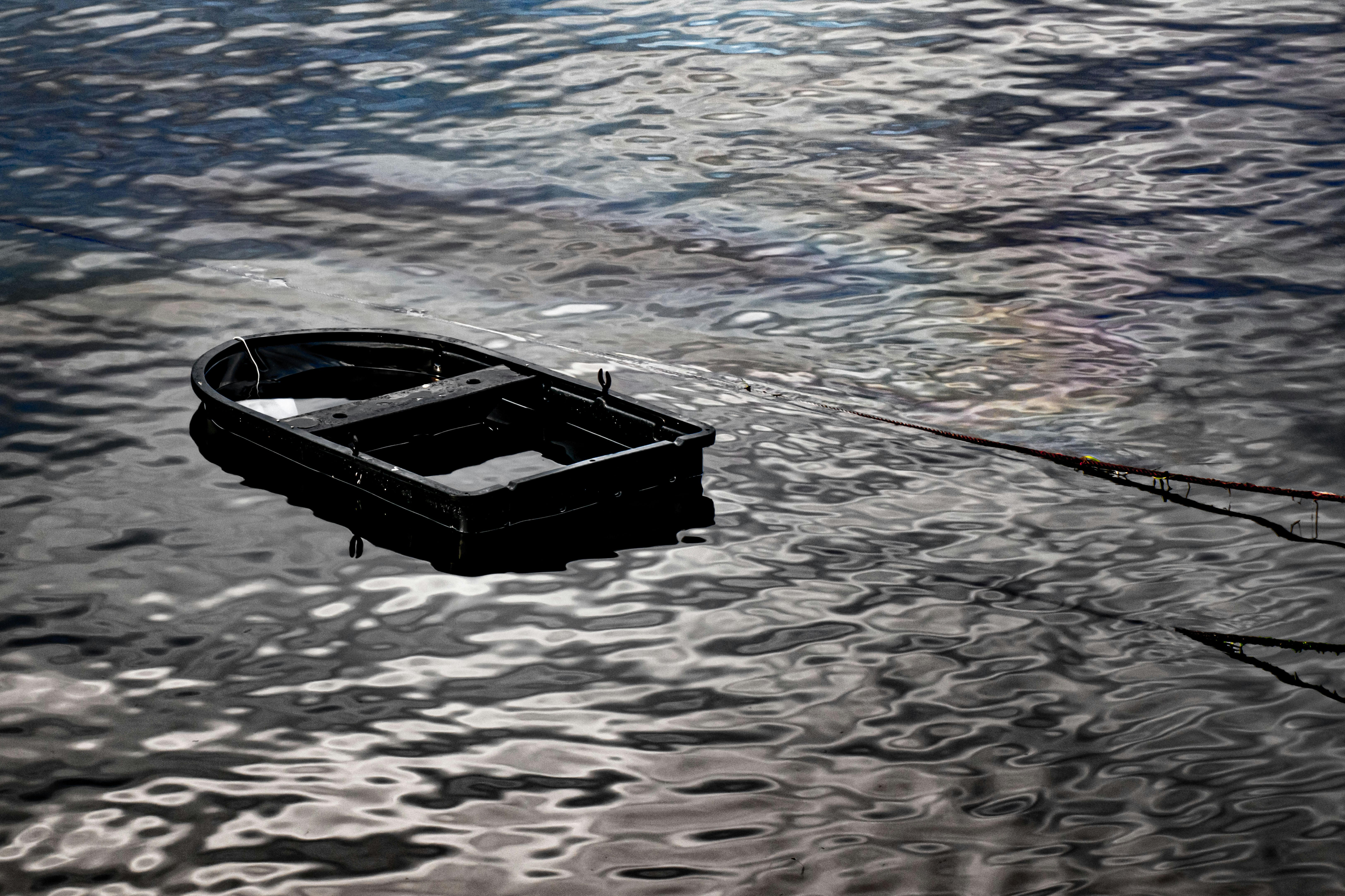 A small black boat frame floating on dark rippling water