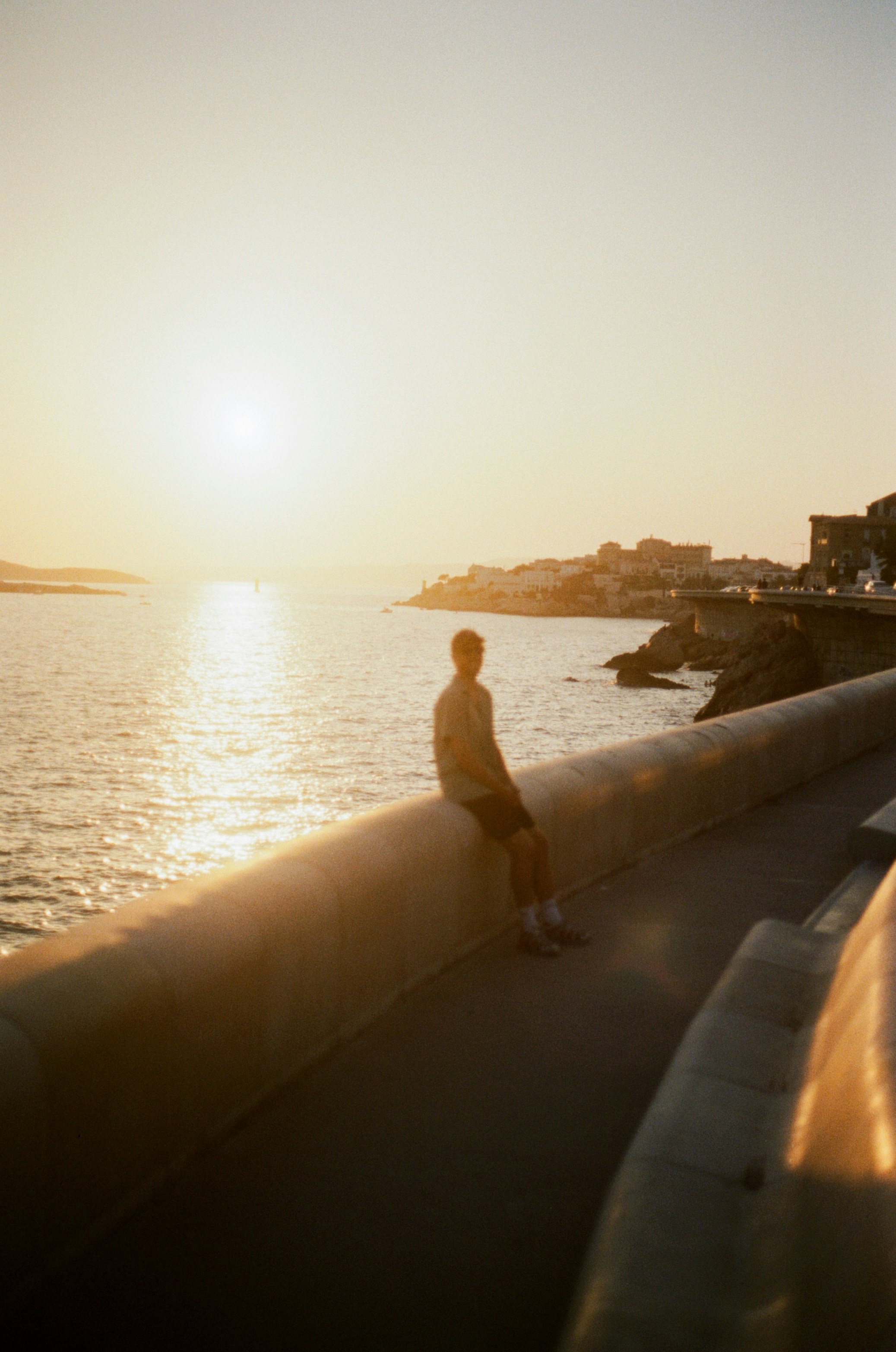 Photo of A person in silhouette on a concrete wall overlooking the sea at low sun by Babi Kacharava