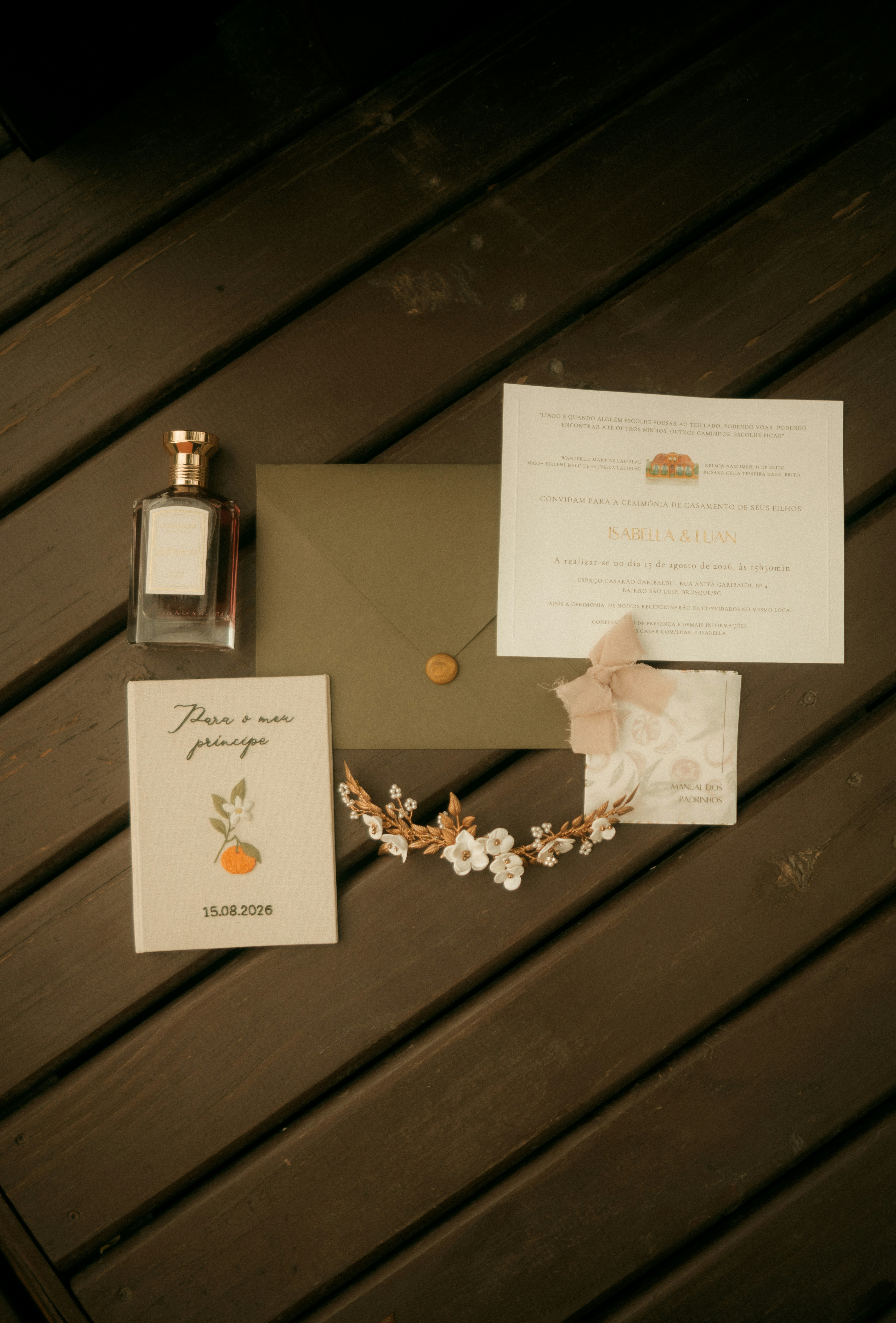 Suite d’invitation de mariage avec une bouteille de parfum et un accessoire floral pour les cheveux sur des planches de bois