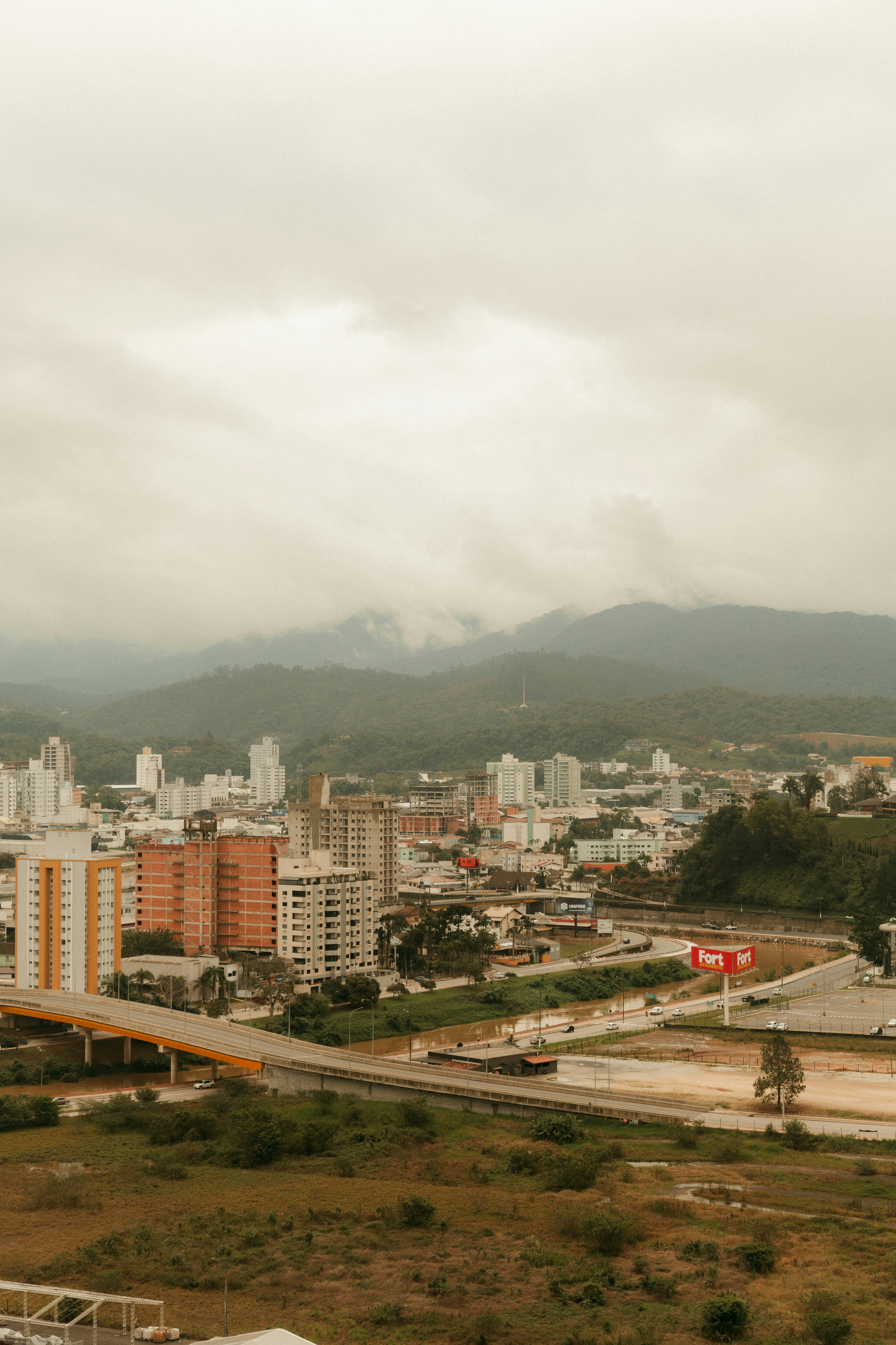 Une silhouette urbaine avec des immeubles de grande hauteur et un pont autoroutier sous un ciel nuageux