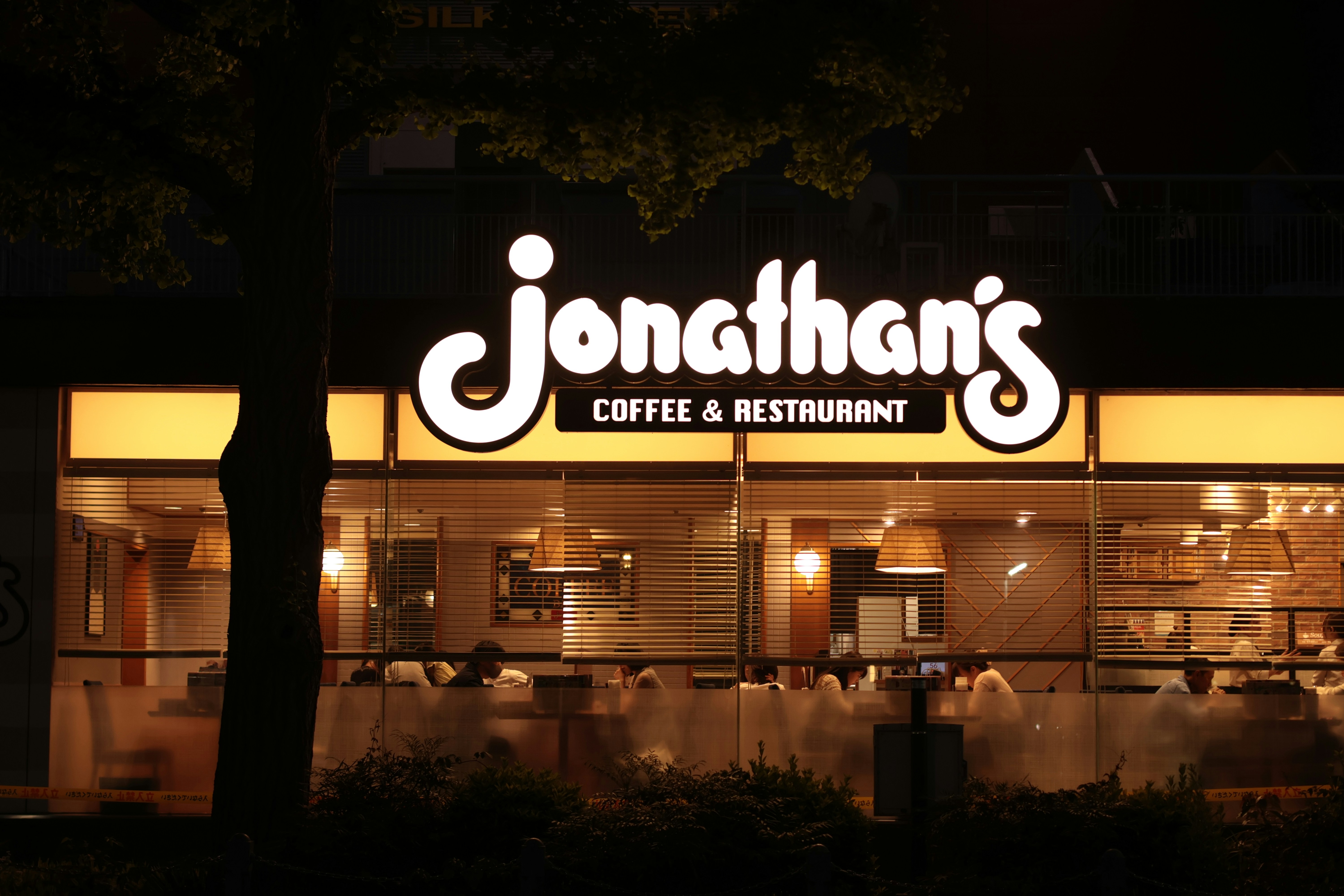 夜、窓のある店の上で光るジョナサンズ・コーヒー&レストランの看板