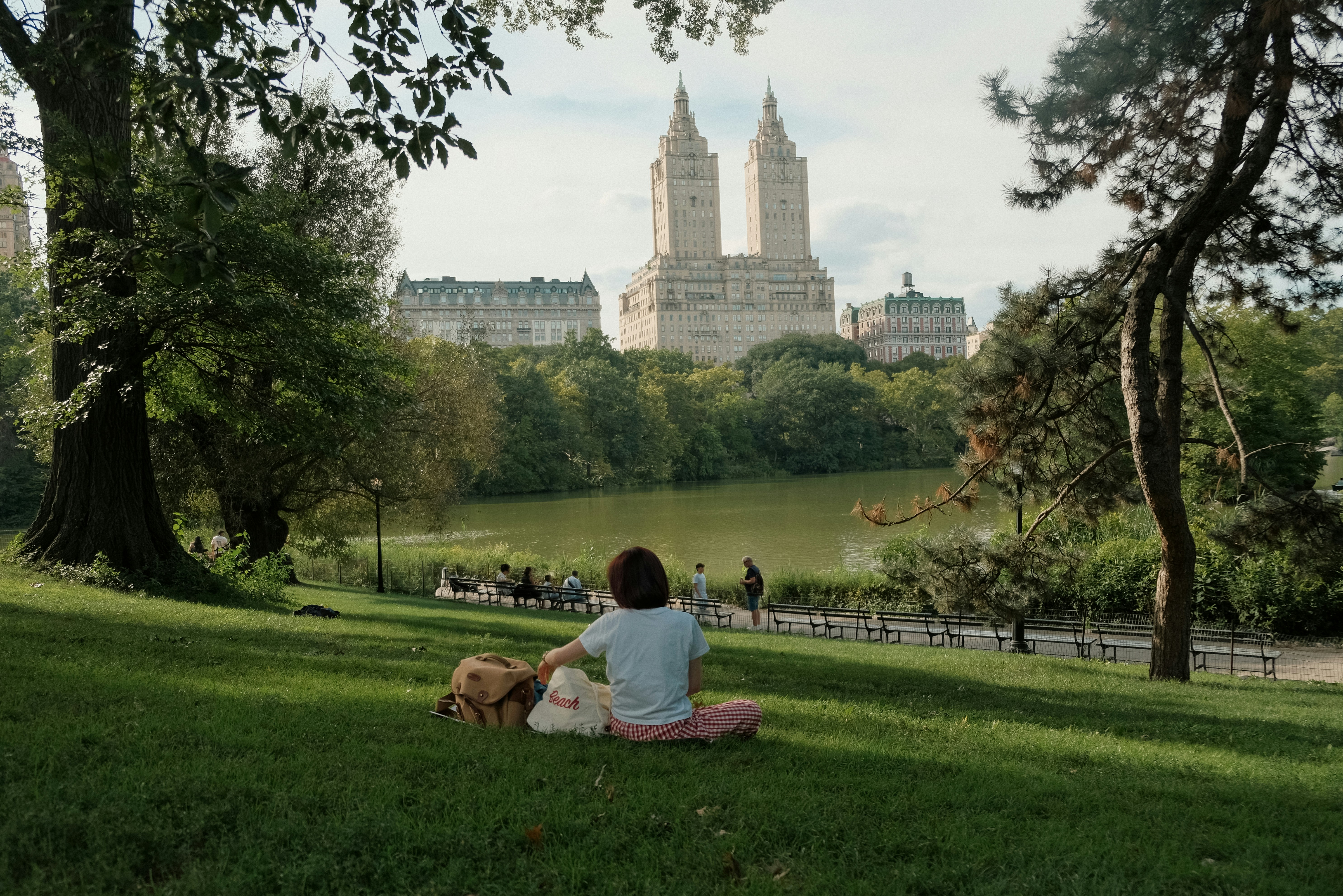 Photo of A person sitting on a grassy hill overlooking The Lake in Central Park by Duong Nguyen