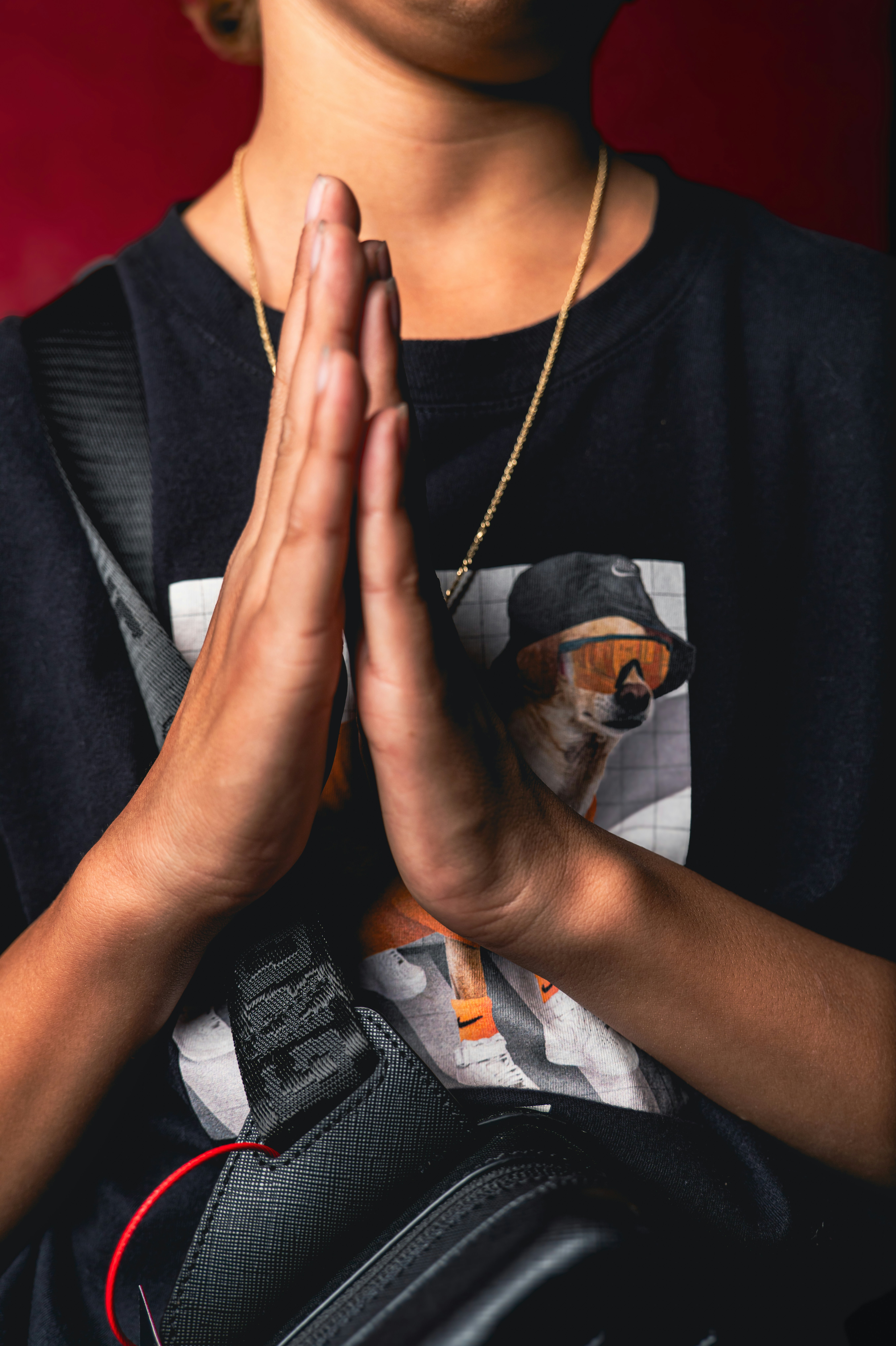 A person with hands pressed together in a black t-shirt with a dog graphic
