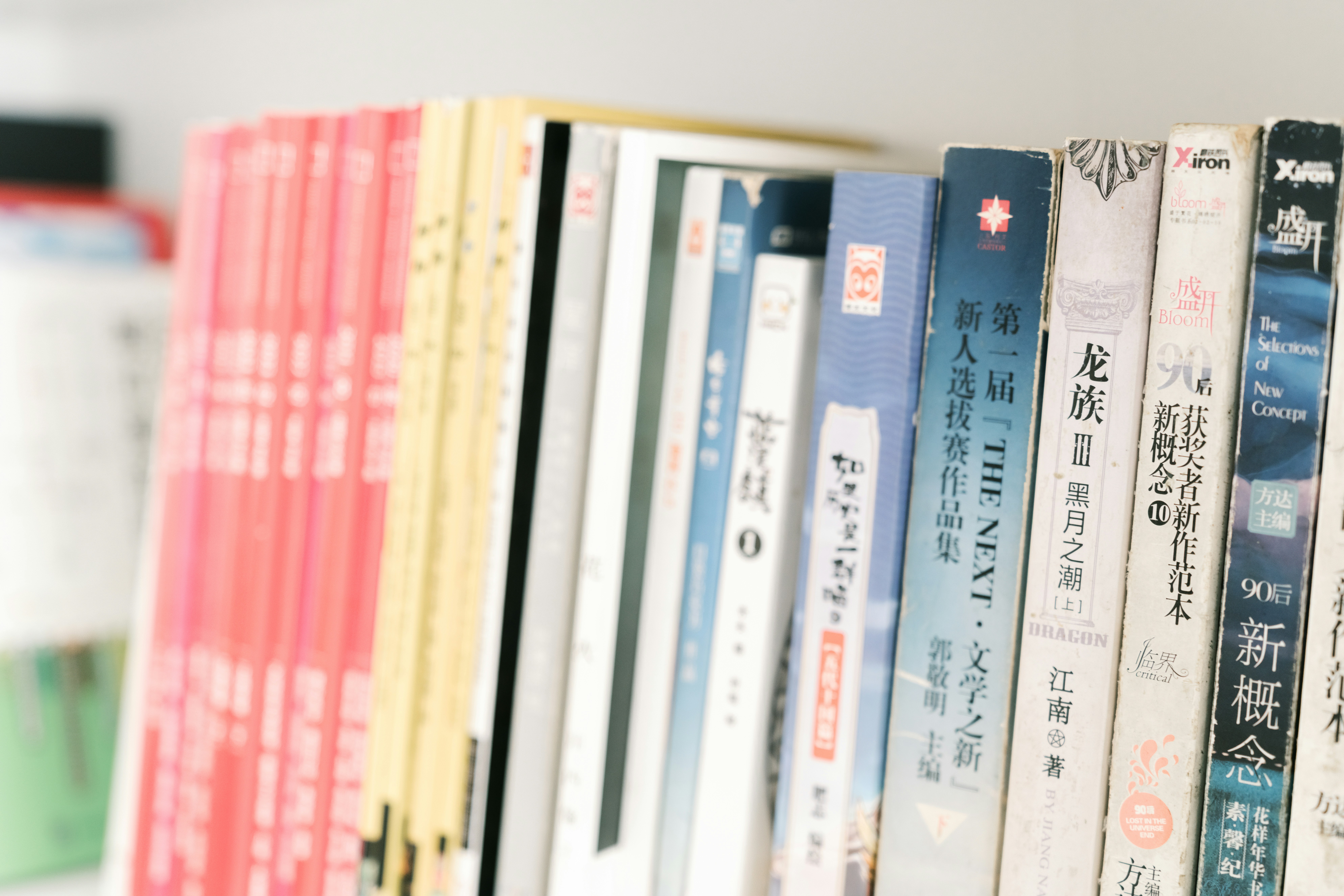 A row of books with colorful spines standing on a shelf