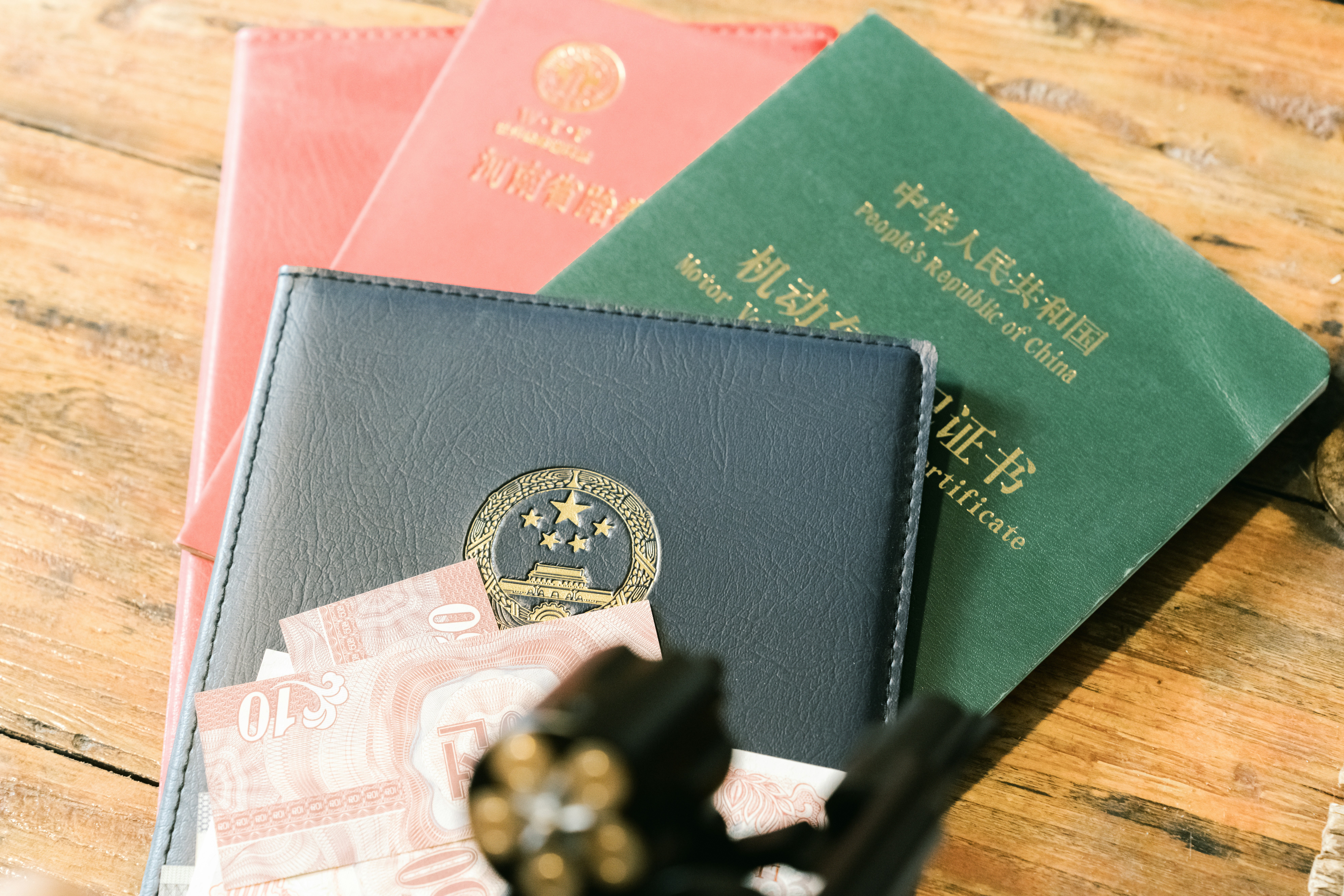 Three Chinese identification documents and paper currency on a rustic wooden surface