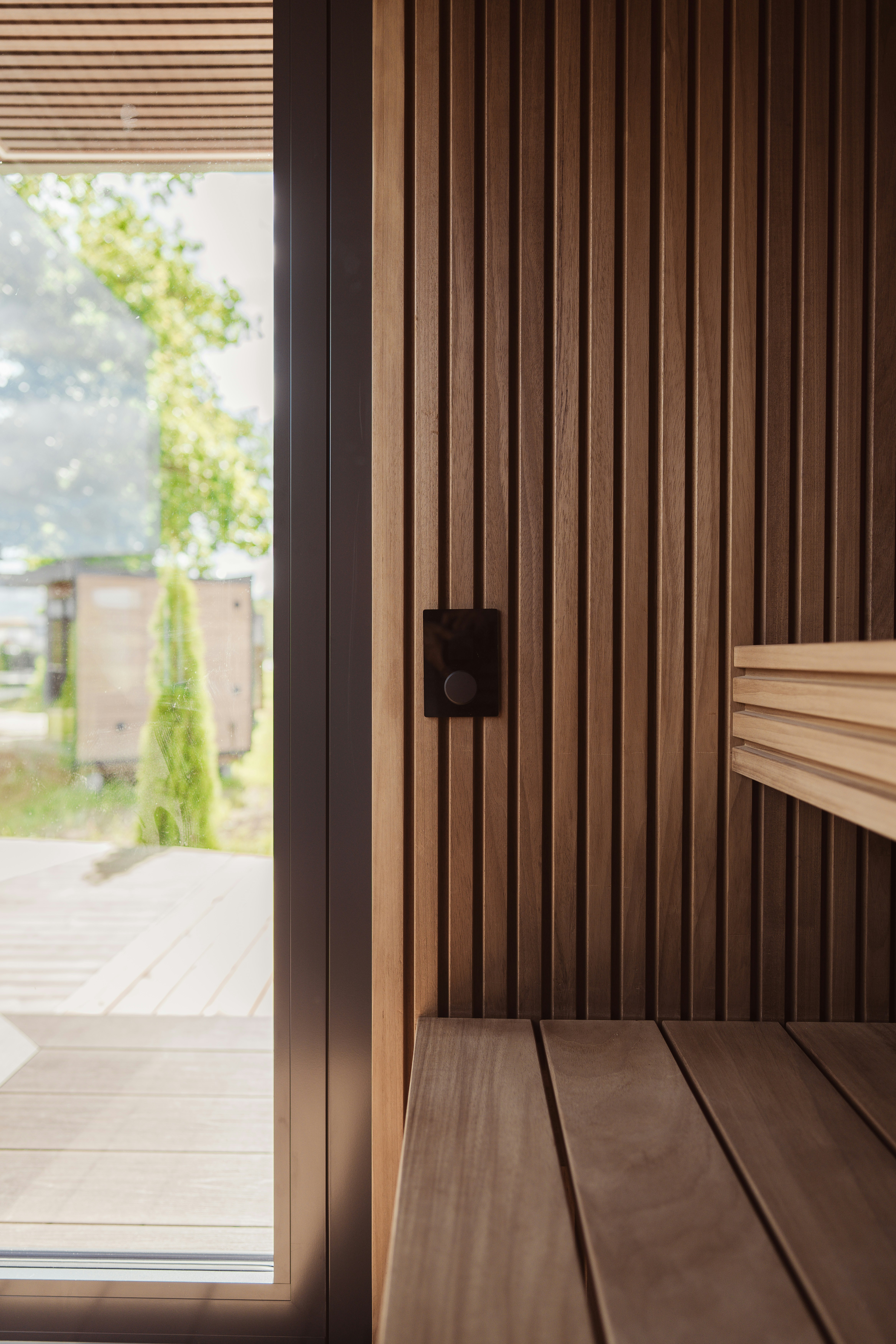 Um interruptor de luz preta em uma parede de madeira com ripas dentro de uma sauna