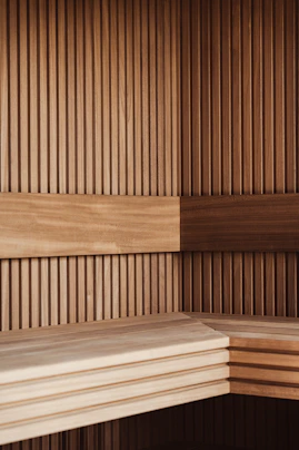 A corner of a sauna with vertical wooden slats and horizontal bench planks