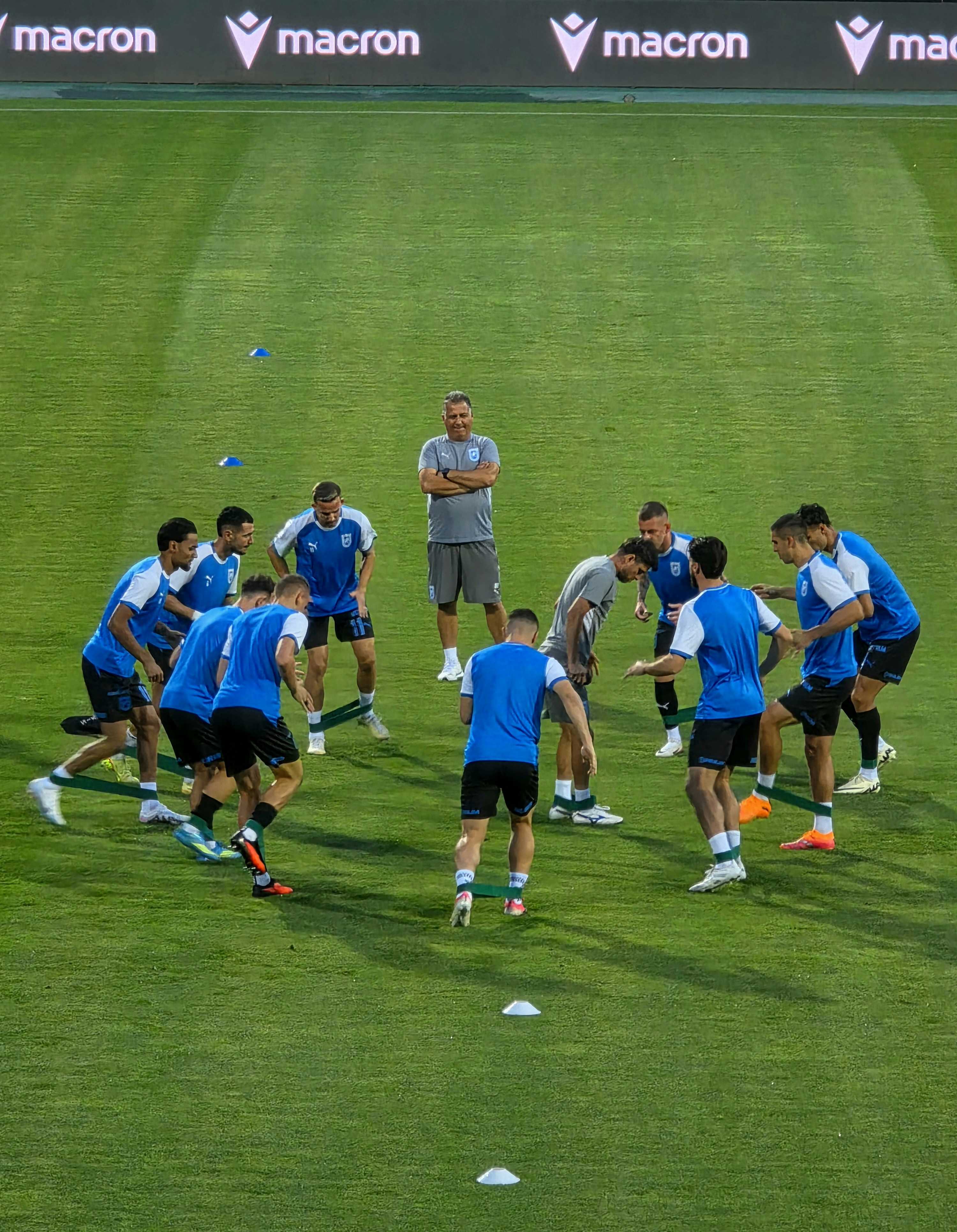 A group of soccer players using resistance bands on a green field