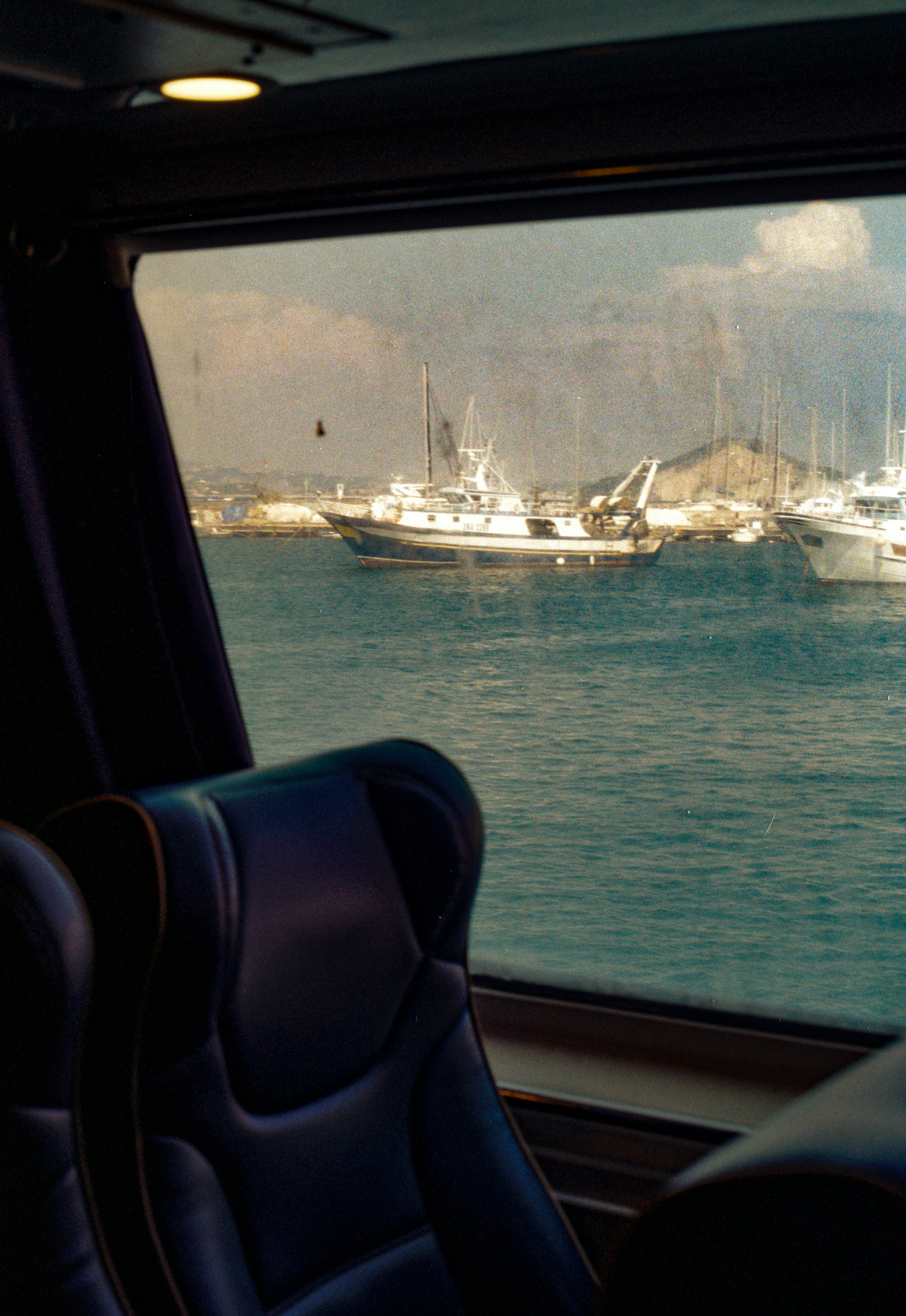 Barcos pesqueros en el agua vistos a través de una ventana oscura de tren