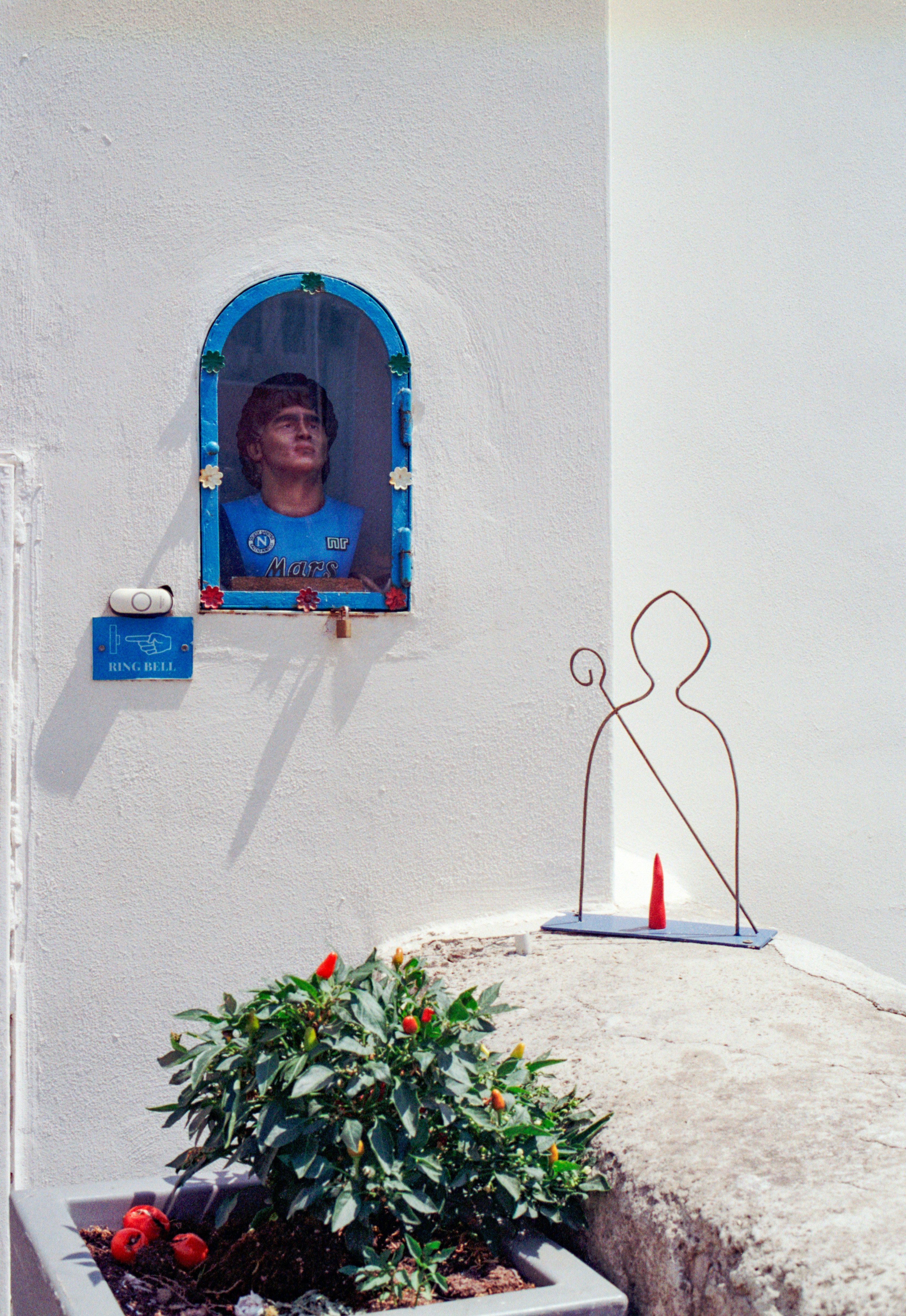 Un busto de un hombre con camiseta azul dentro de un nicho en la pared