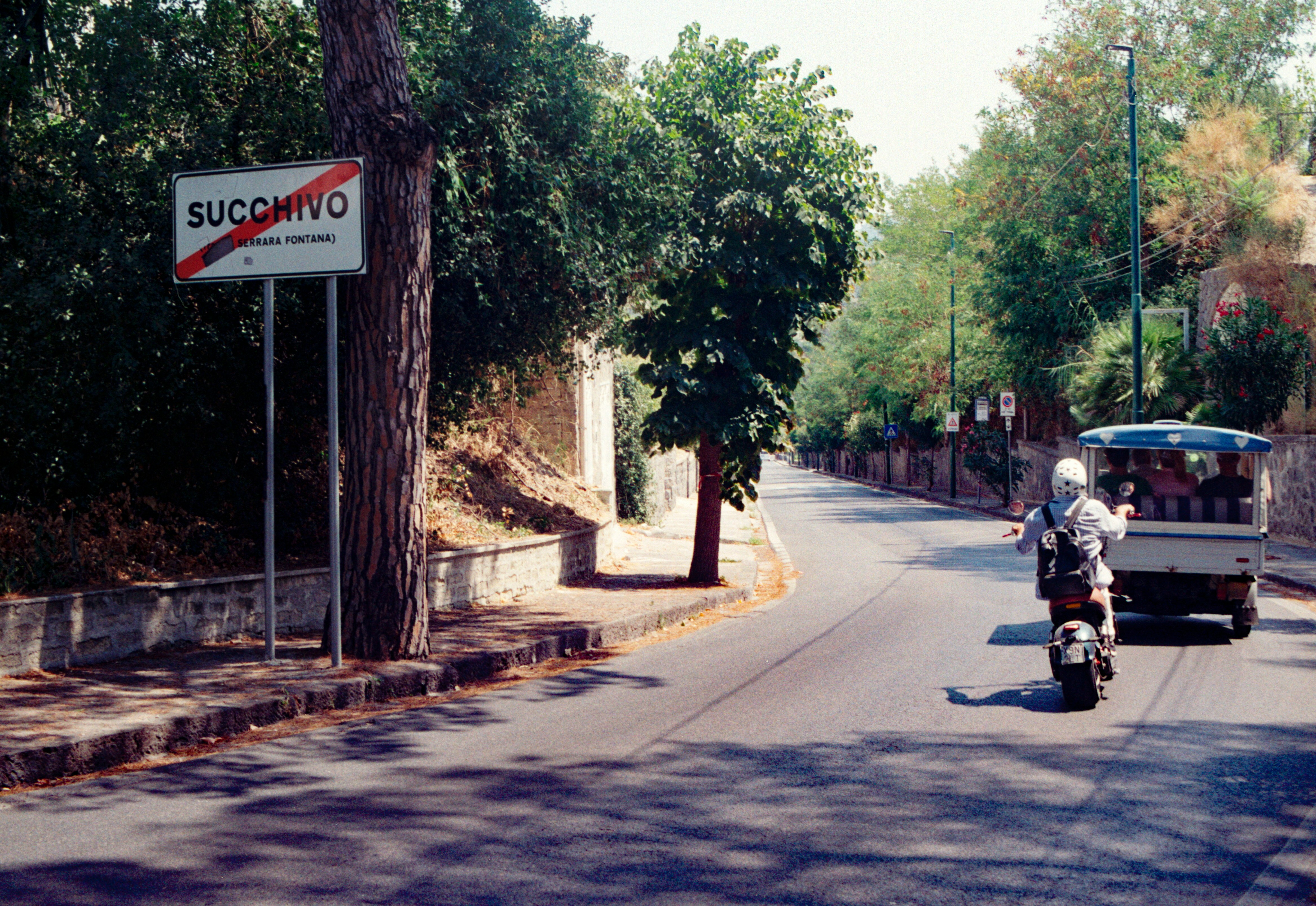Una motocicleta y un pequeño vehículo de tres ruedas en una carretera de Succhivo, Italia