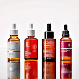 Four amber glass dropper bottles of facial oil on a reflective white surface