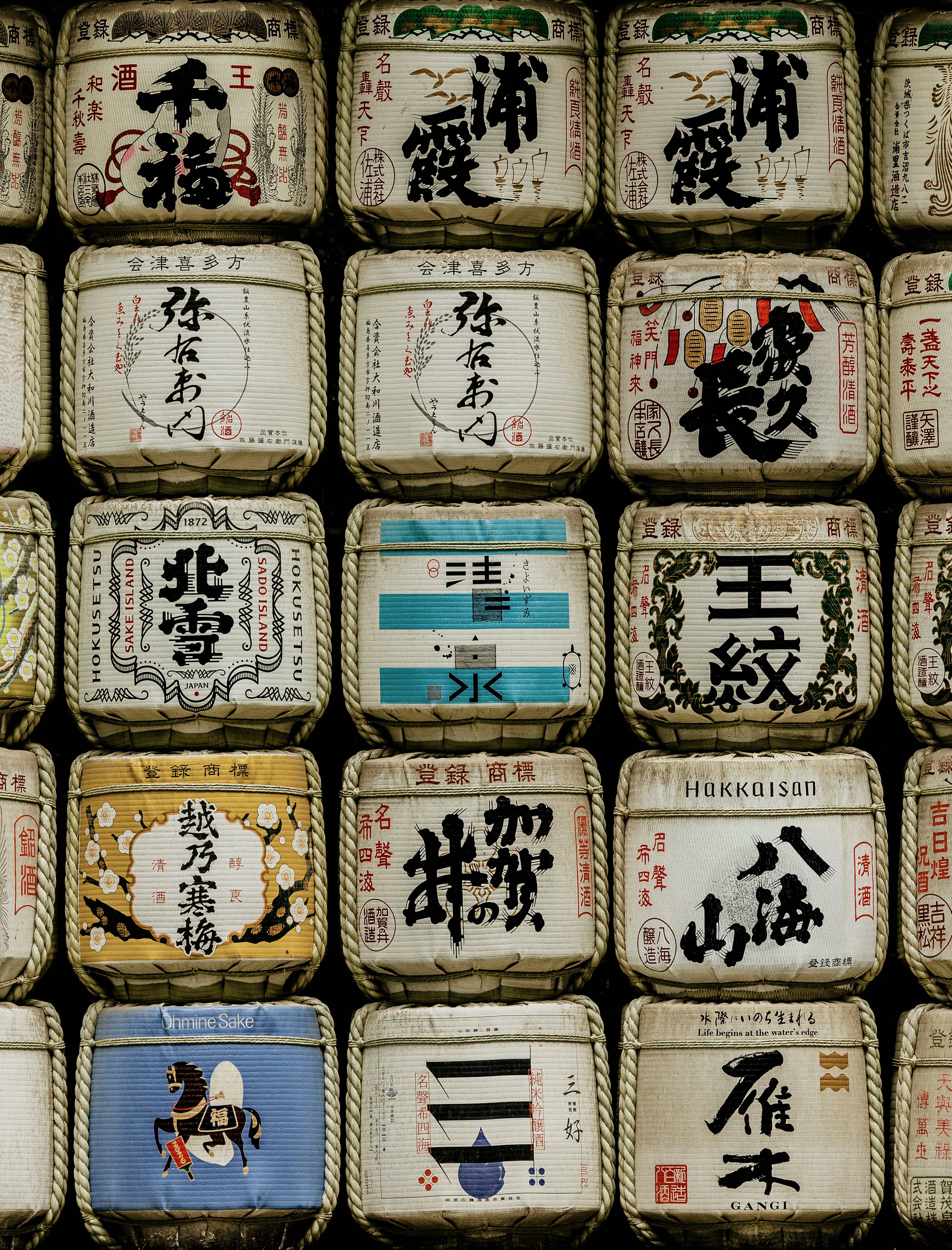 Un mur de tonneaux de saké empilés avec des calligraphies japonaises traditionnelles et des labels décoratifs