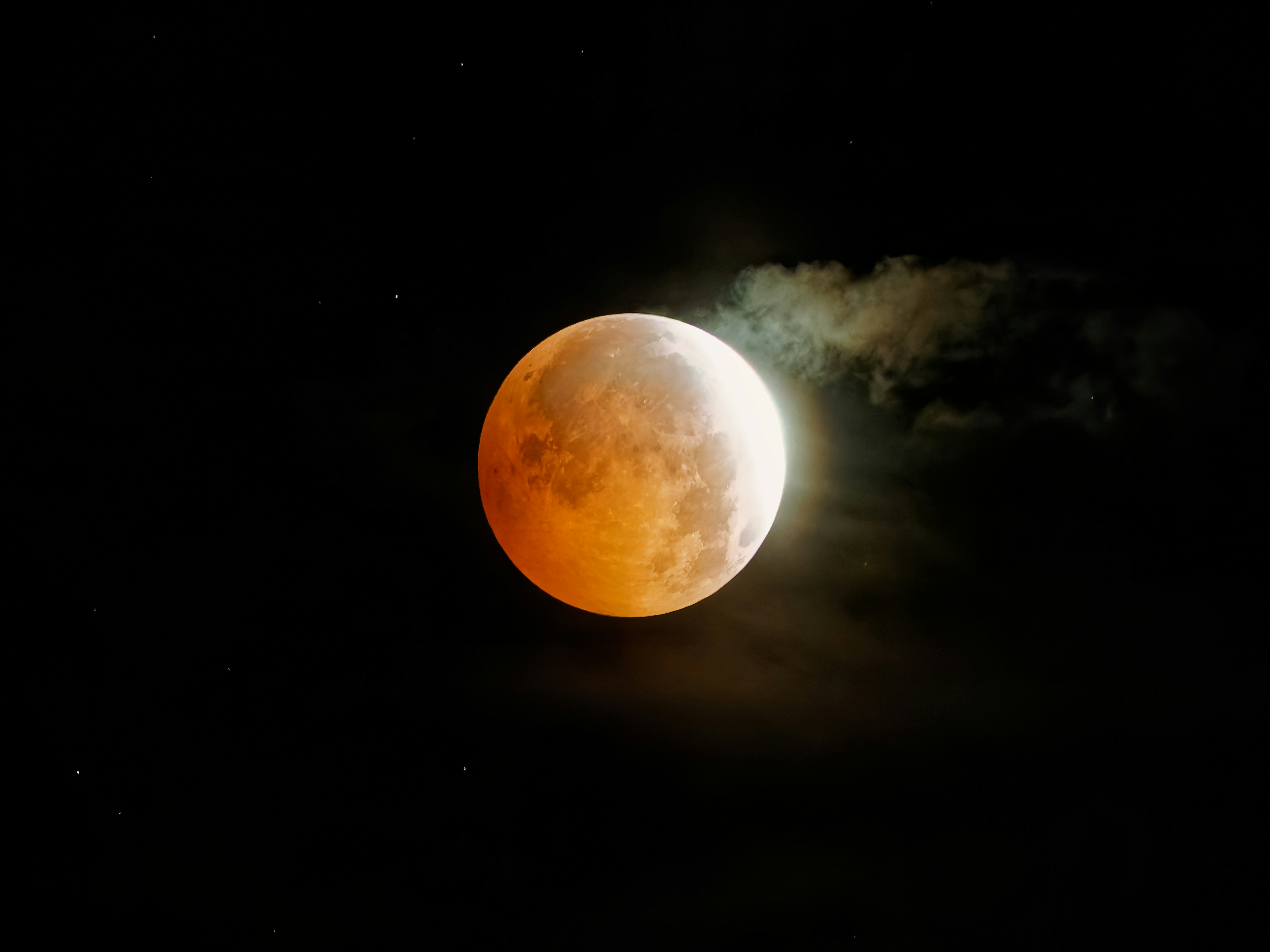 Photo of A partial lunar eclipse glowing orange against a dark night sky with scattered stars by Red Zeppelin