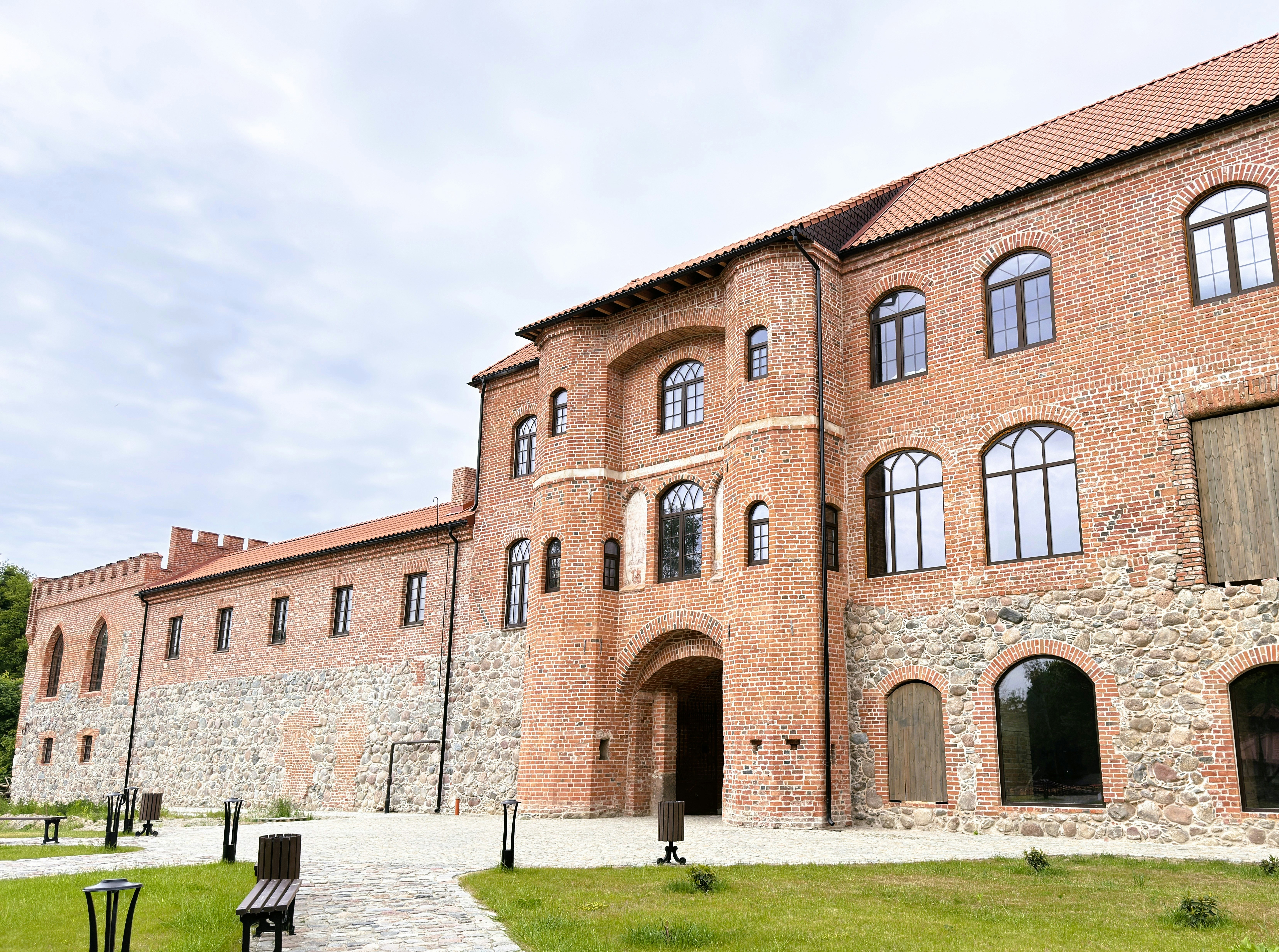 A historic red brick building with arched windows and a stone foundation