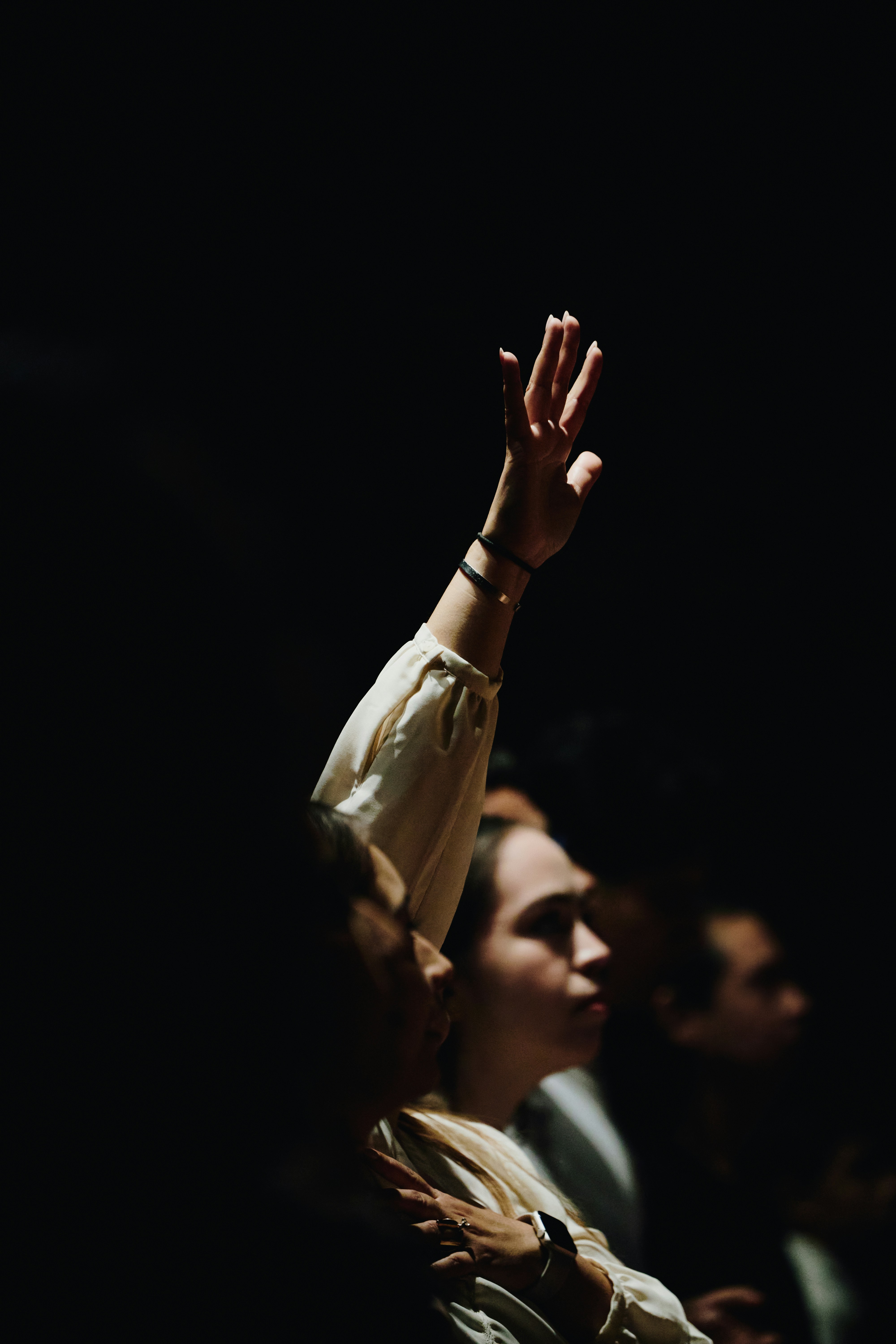 A person with a raised hand in a dimly lit room