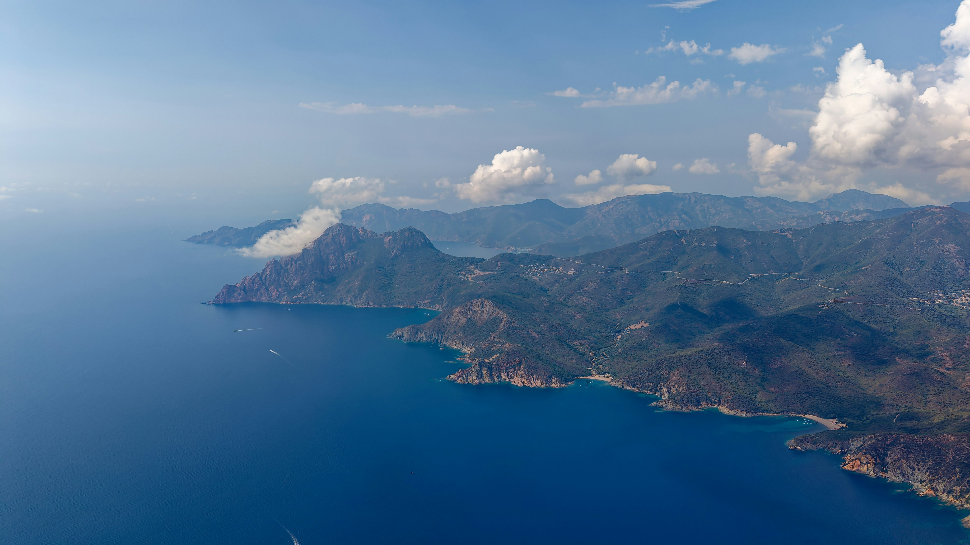 An aerial view of a rugged coastline with mountains meeting the deep blue sea