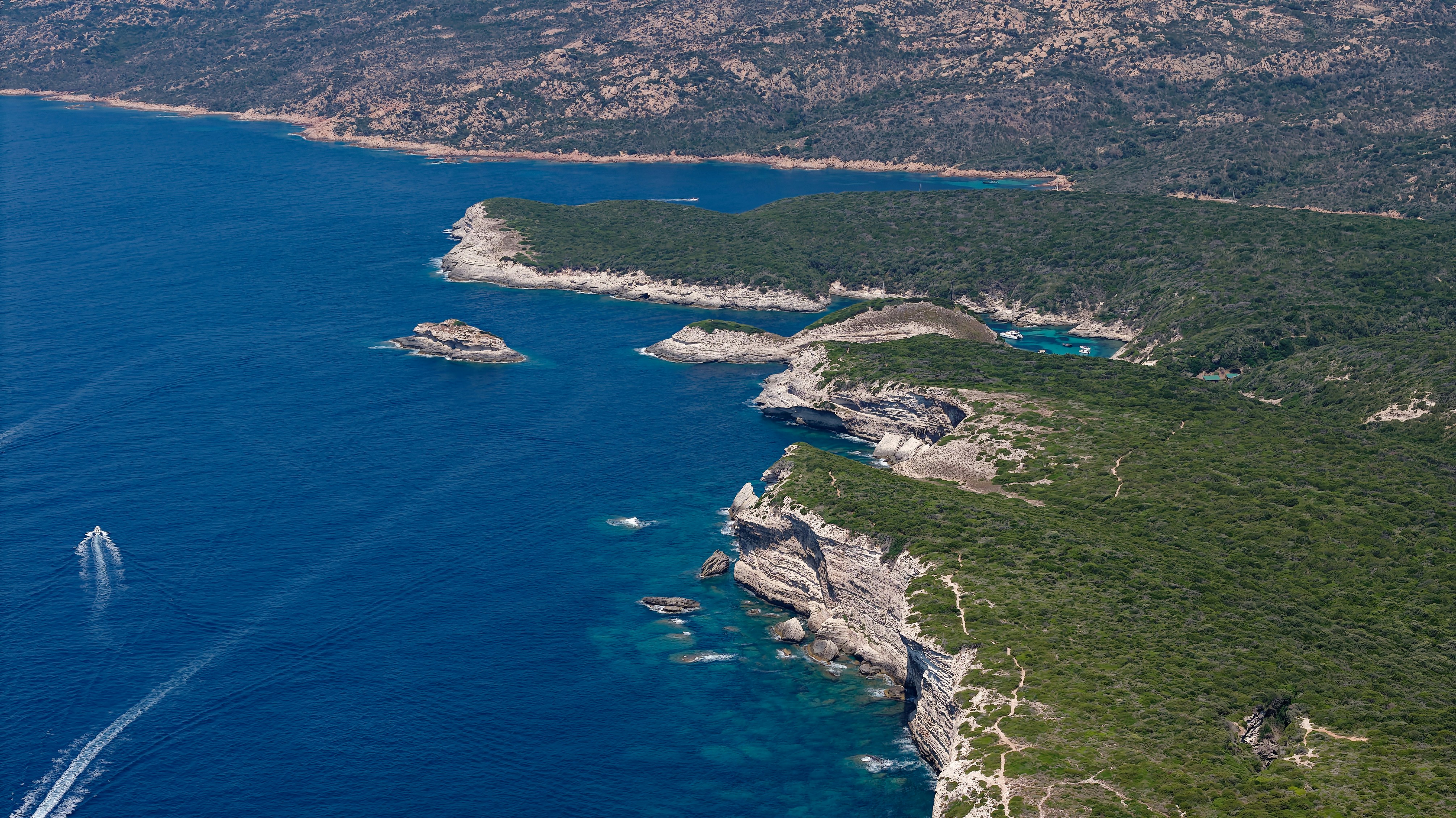 Aerial view of a rugged coastline with white cliffs and a small boat