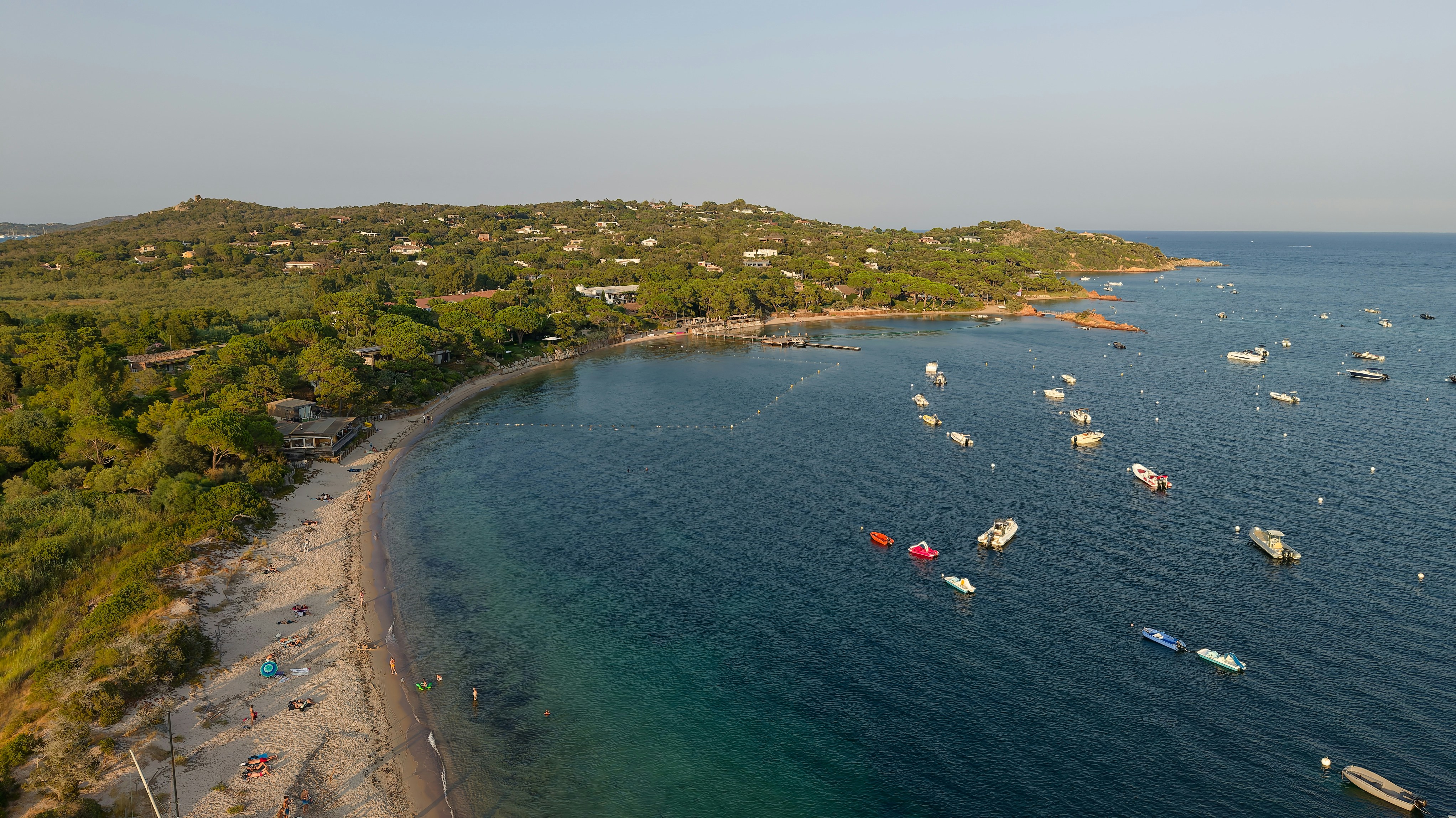 Aerial view of a sandy beach and boats anchored in a calm bay
