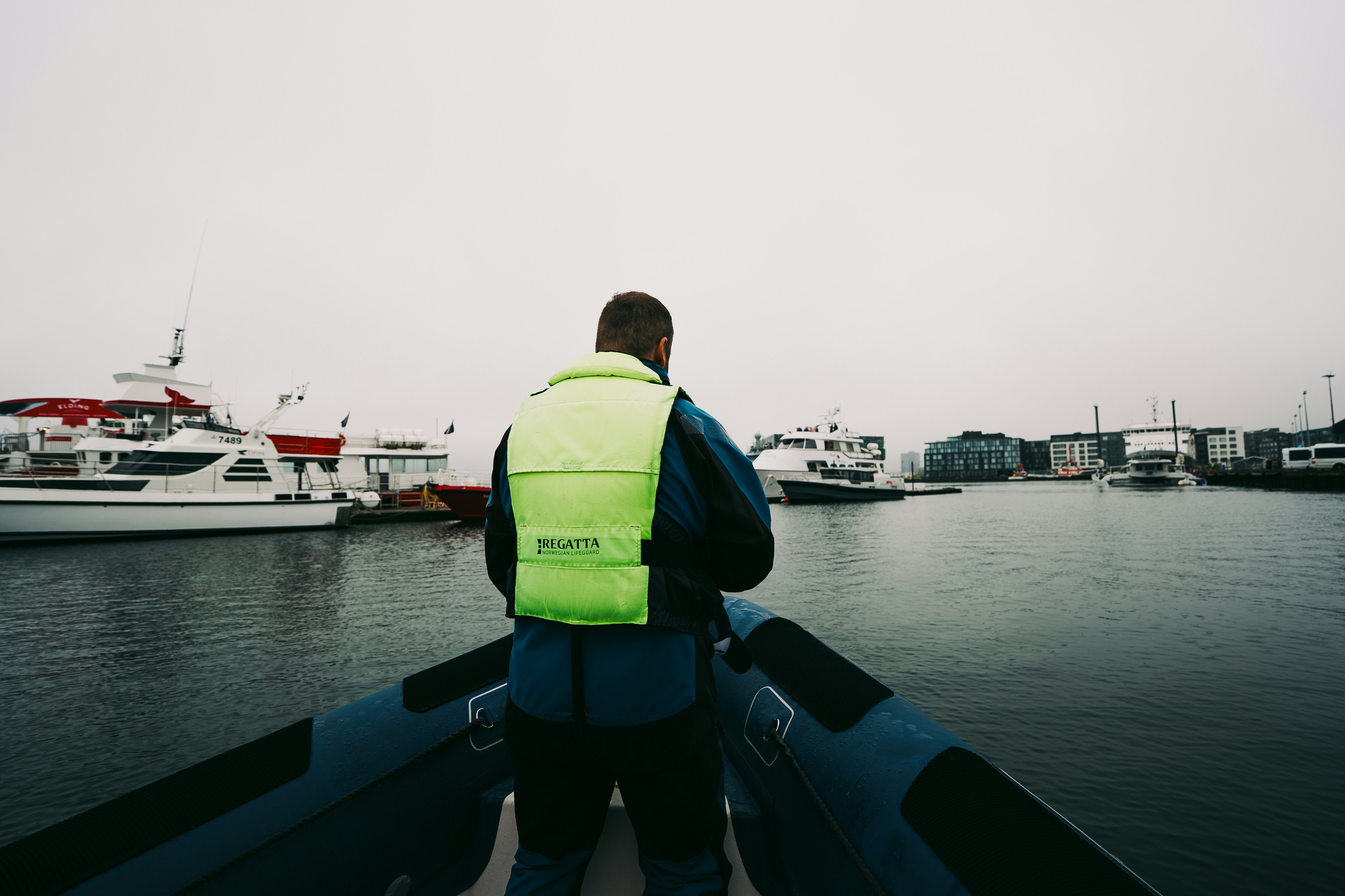 A person in a bright yellow life vest on a boat in a harbor