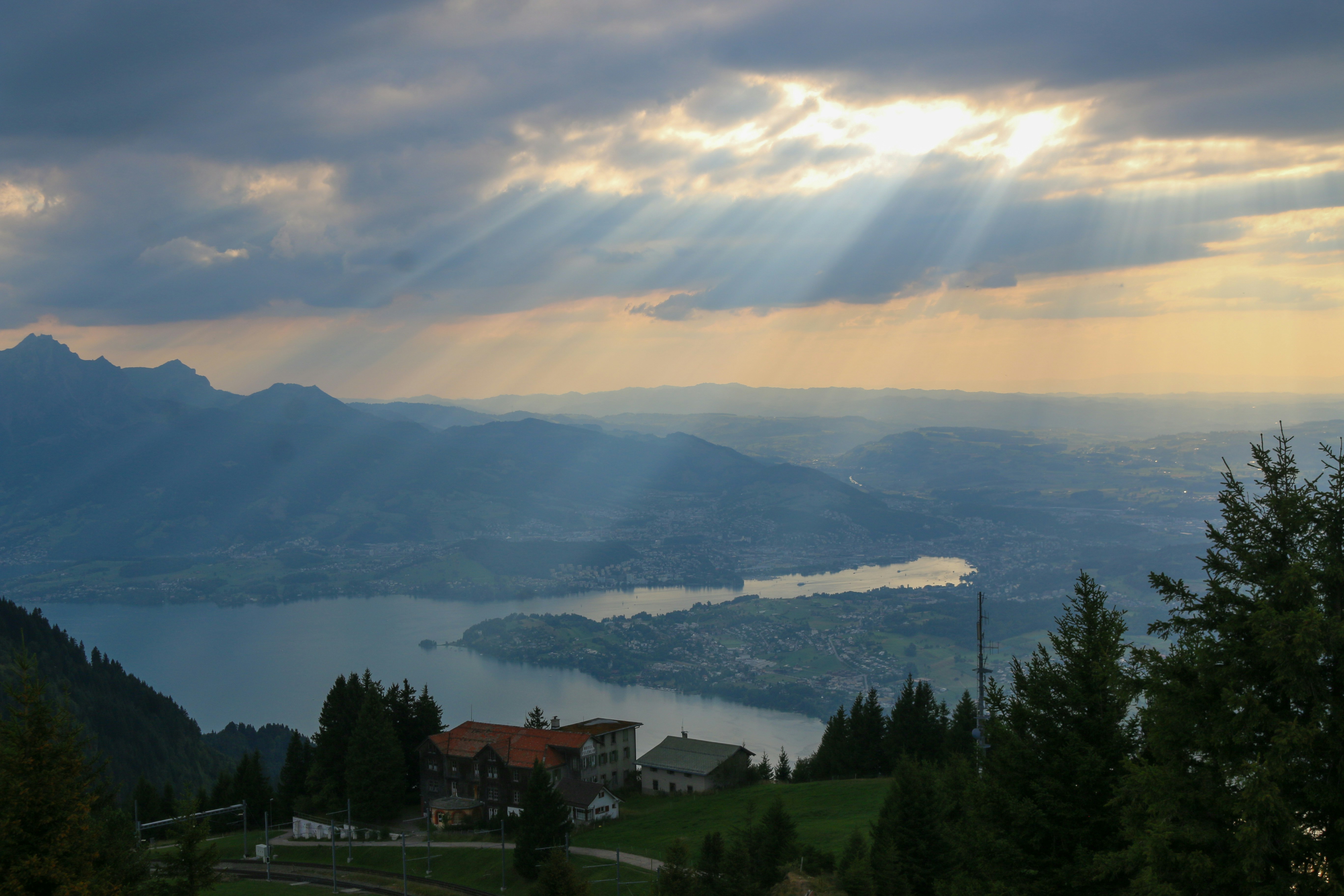 Sunbeams breaking through clouds over a lake and town in the Swiss Alps