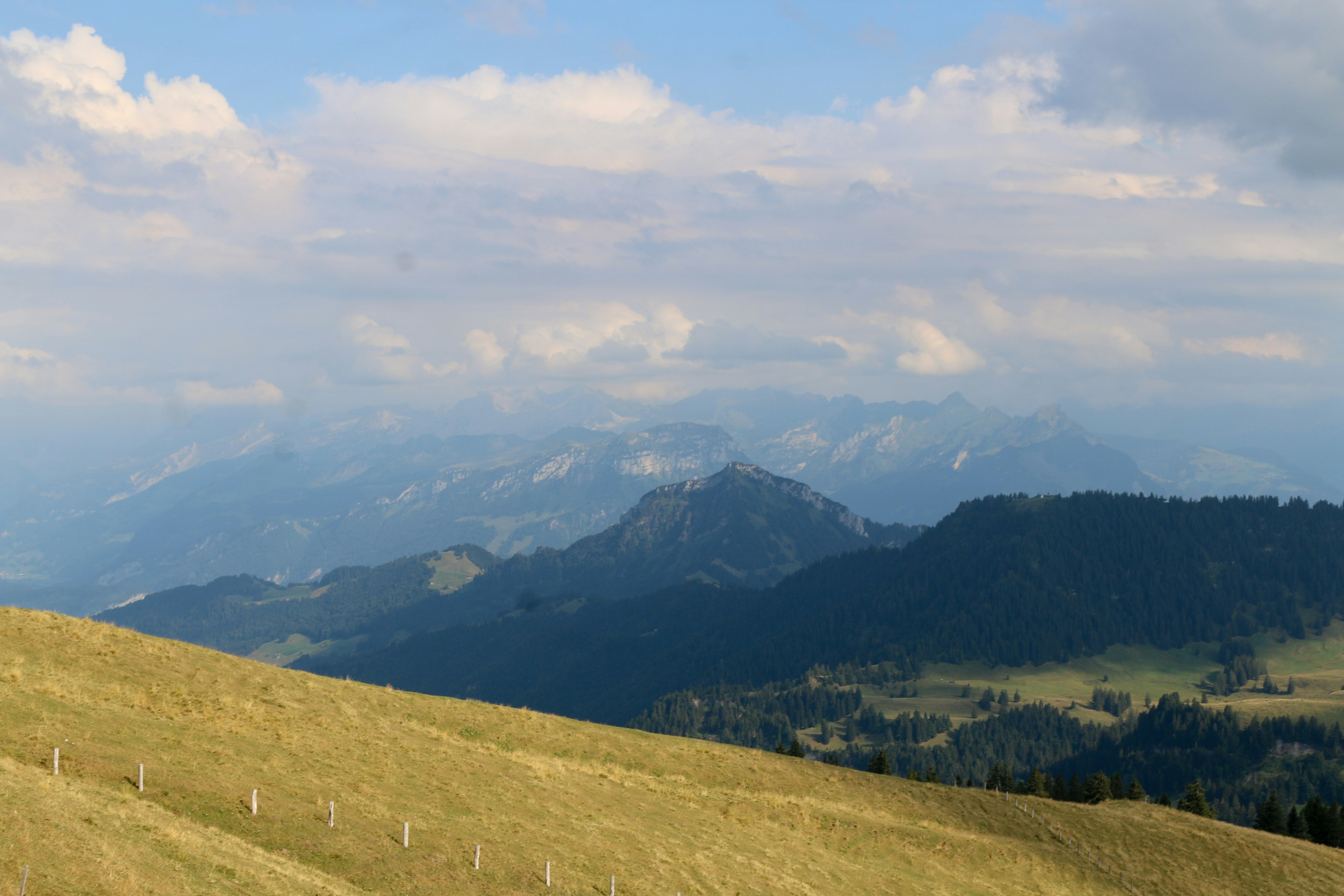 A grassy mountain slope overlooking a vast range of distant blue peaks