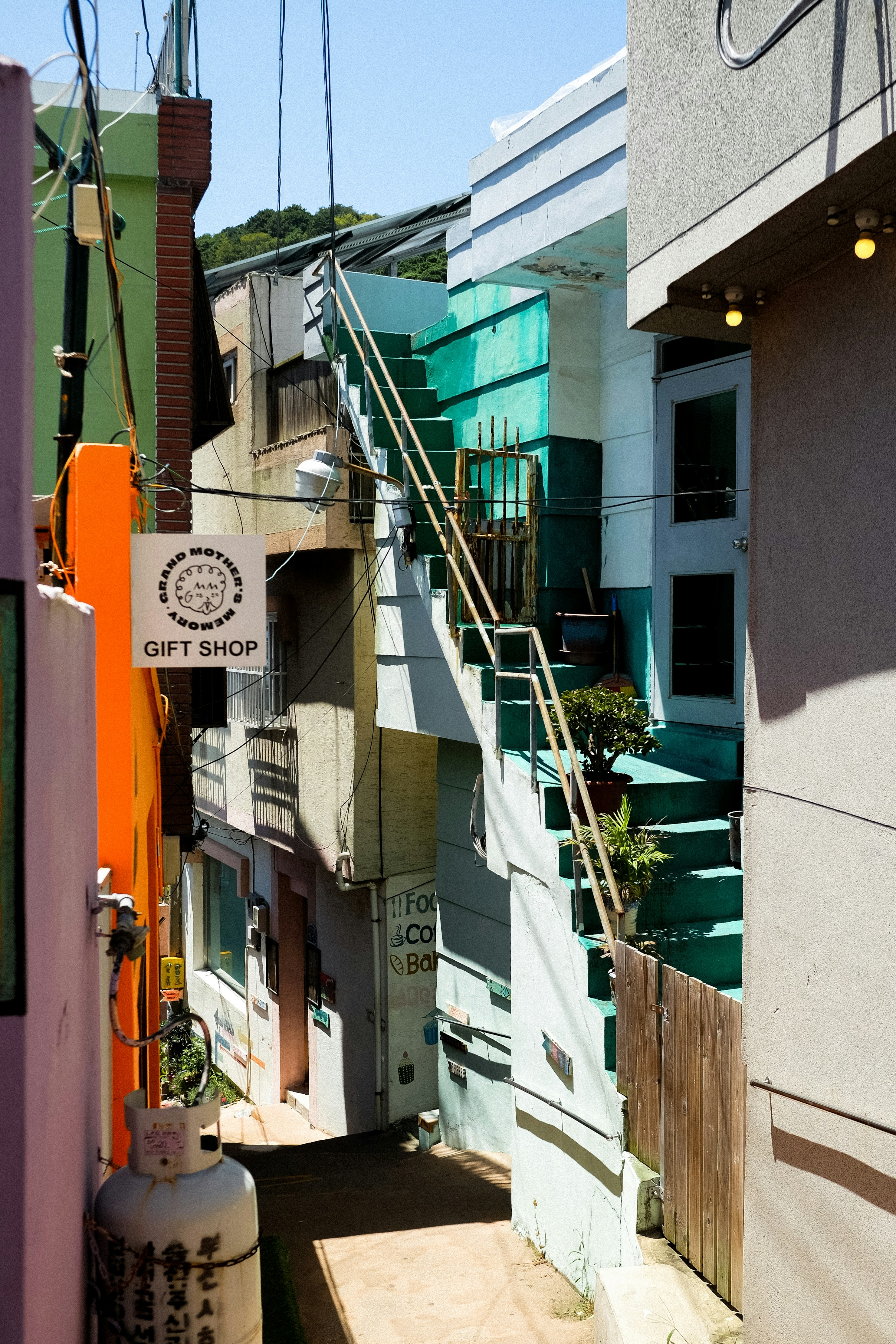 A narrow alleyway with a turquoise staircase leading to a gift shop entrance