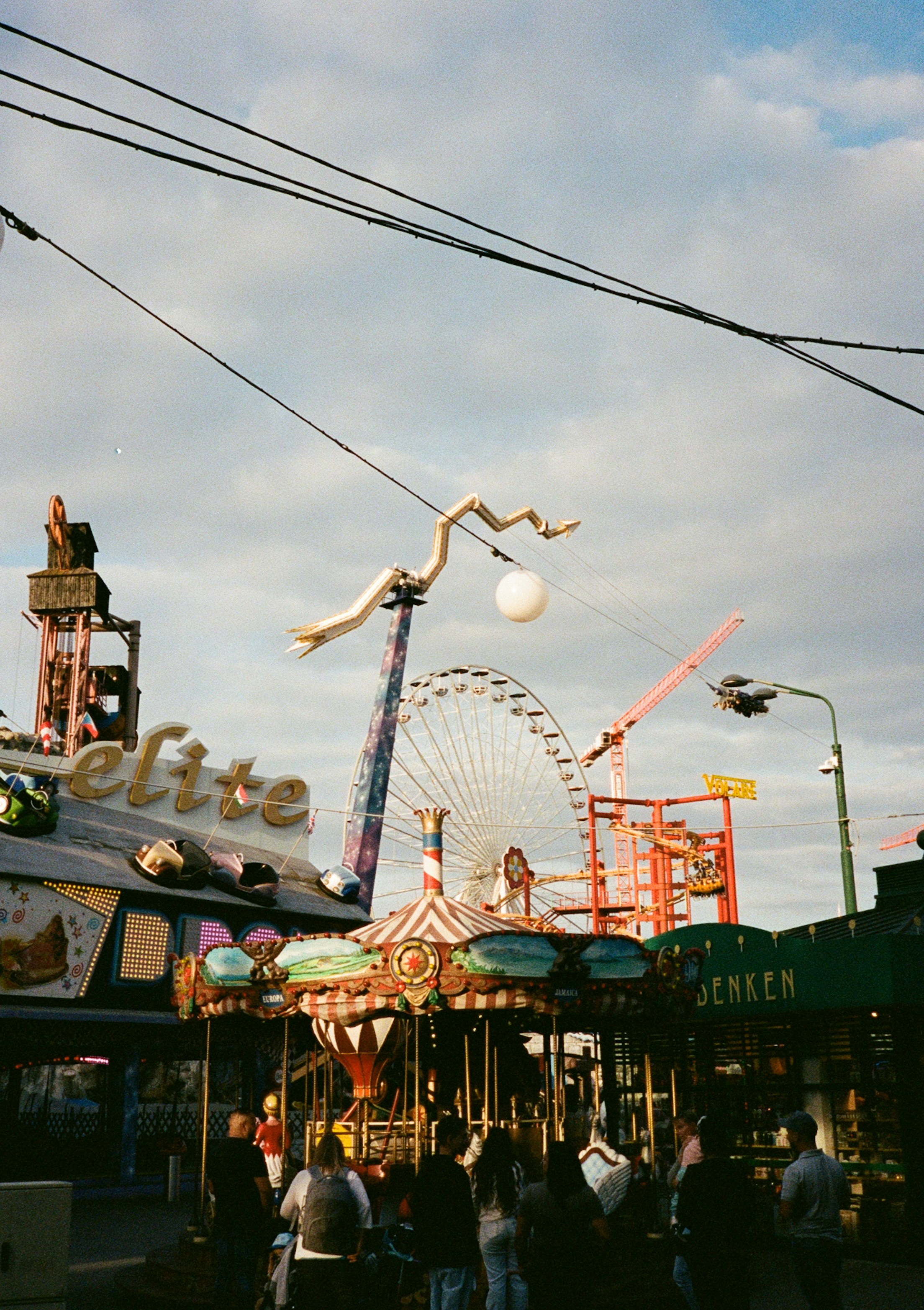 A carousel and amusement park rides under a cloudy sky in Vienna, Austria