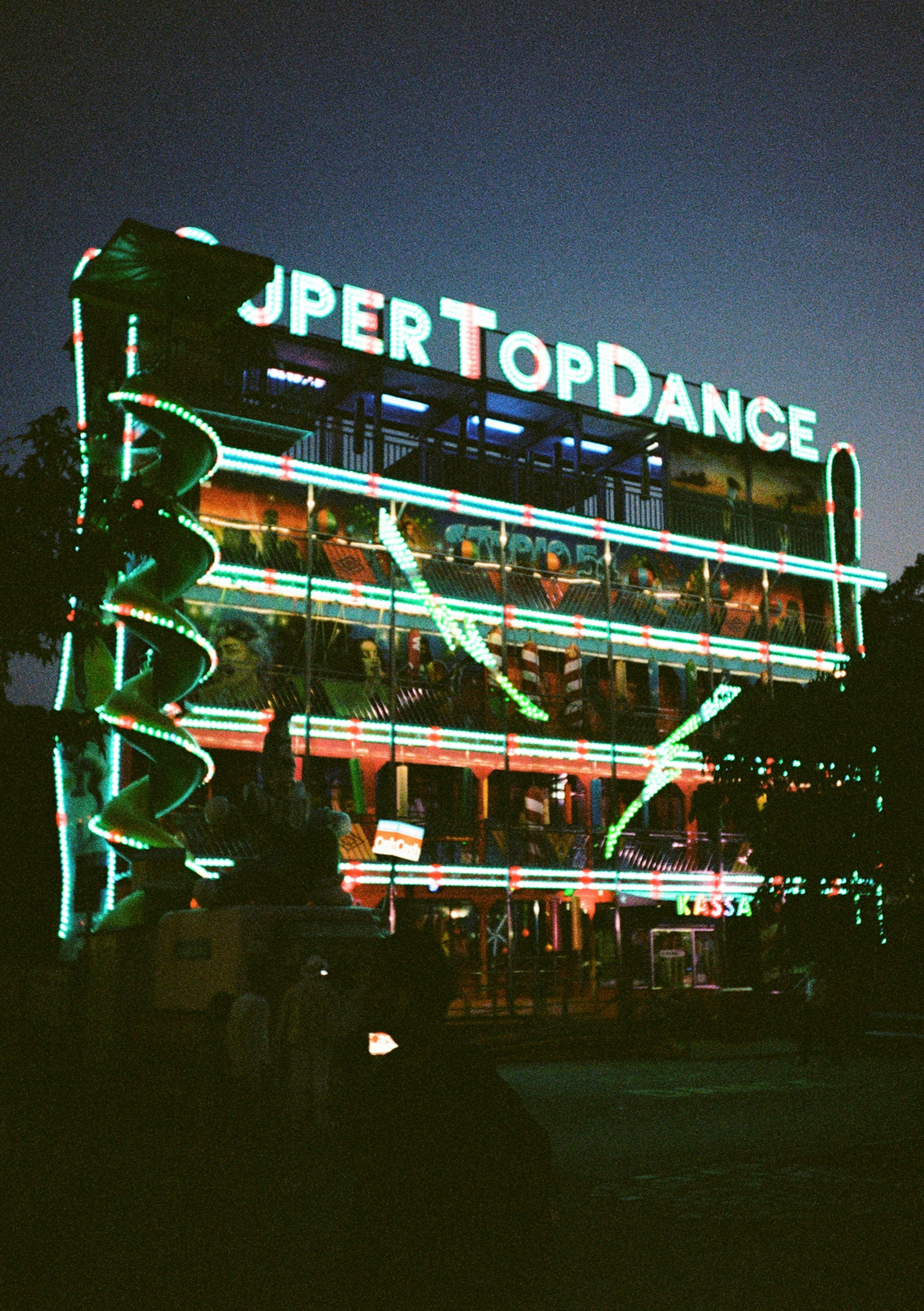 A multi-level funhouse ride with neon lights in Vienna at night
