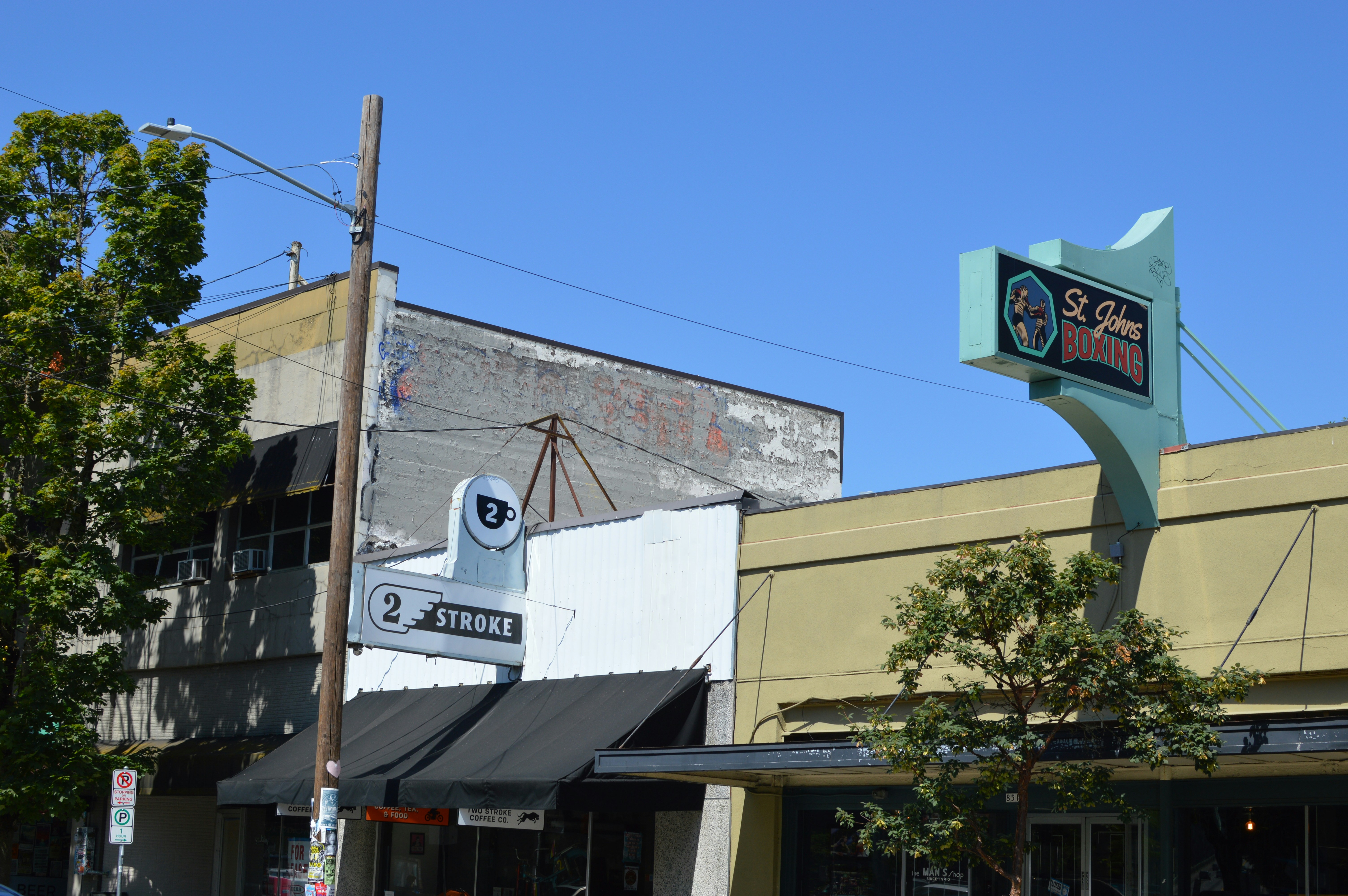 Street signs for St. Johns Boxing and 2 Stroke Coffee Co on a sunny day