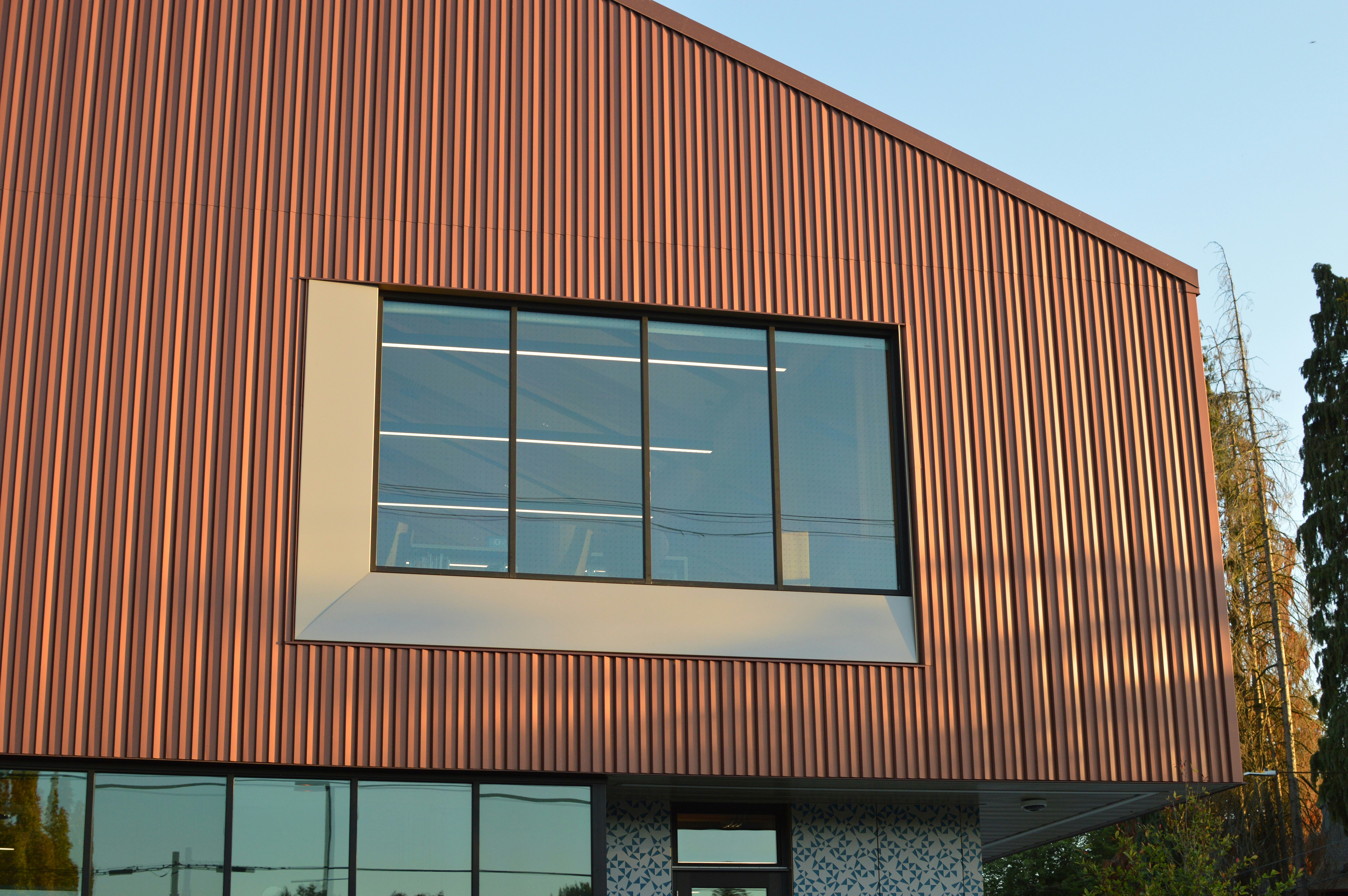 A modern building with corrugated copper siding and a large rectangular window