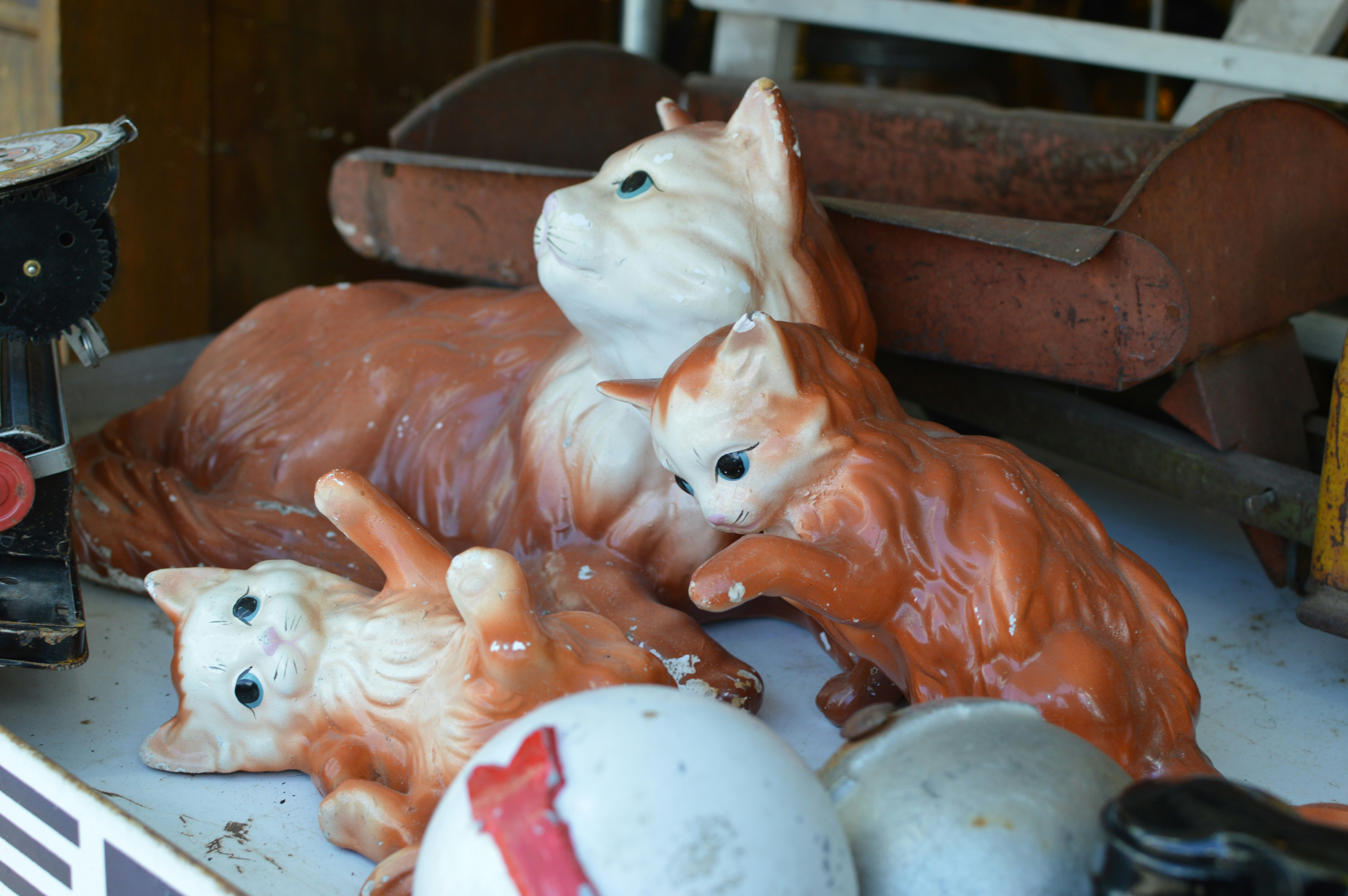 Three orange and white ceramic cat figurines on a white surface