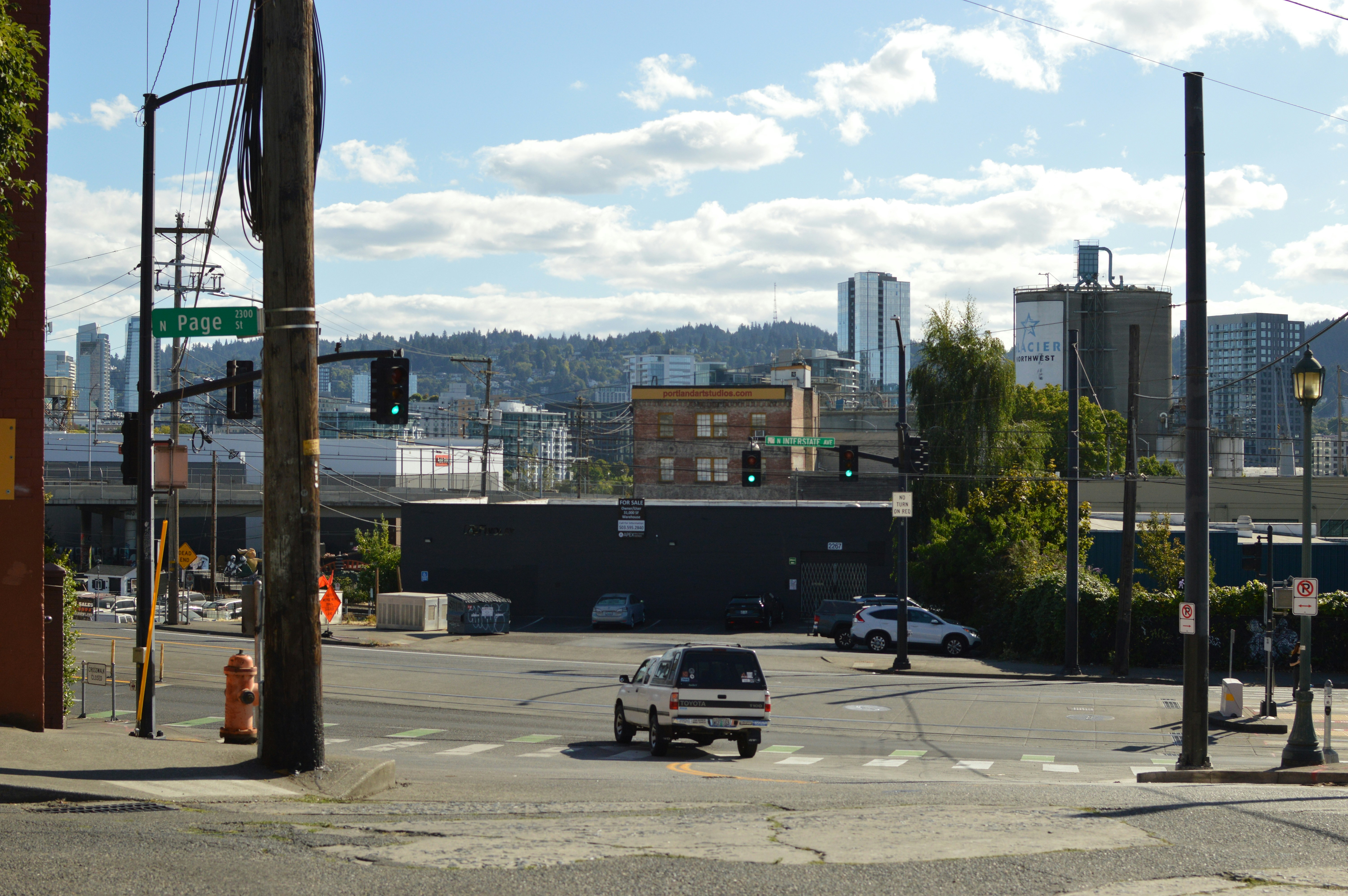 A white pickup truck driving through an intersection in Portland with city buildings behind