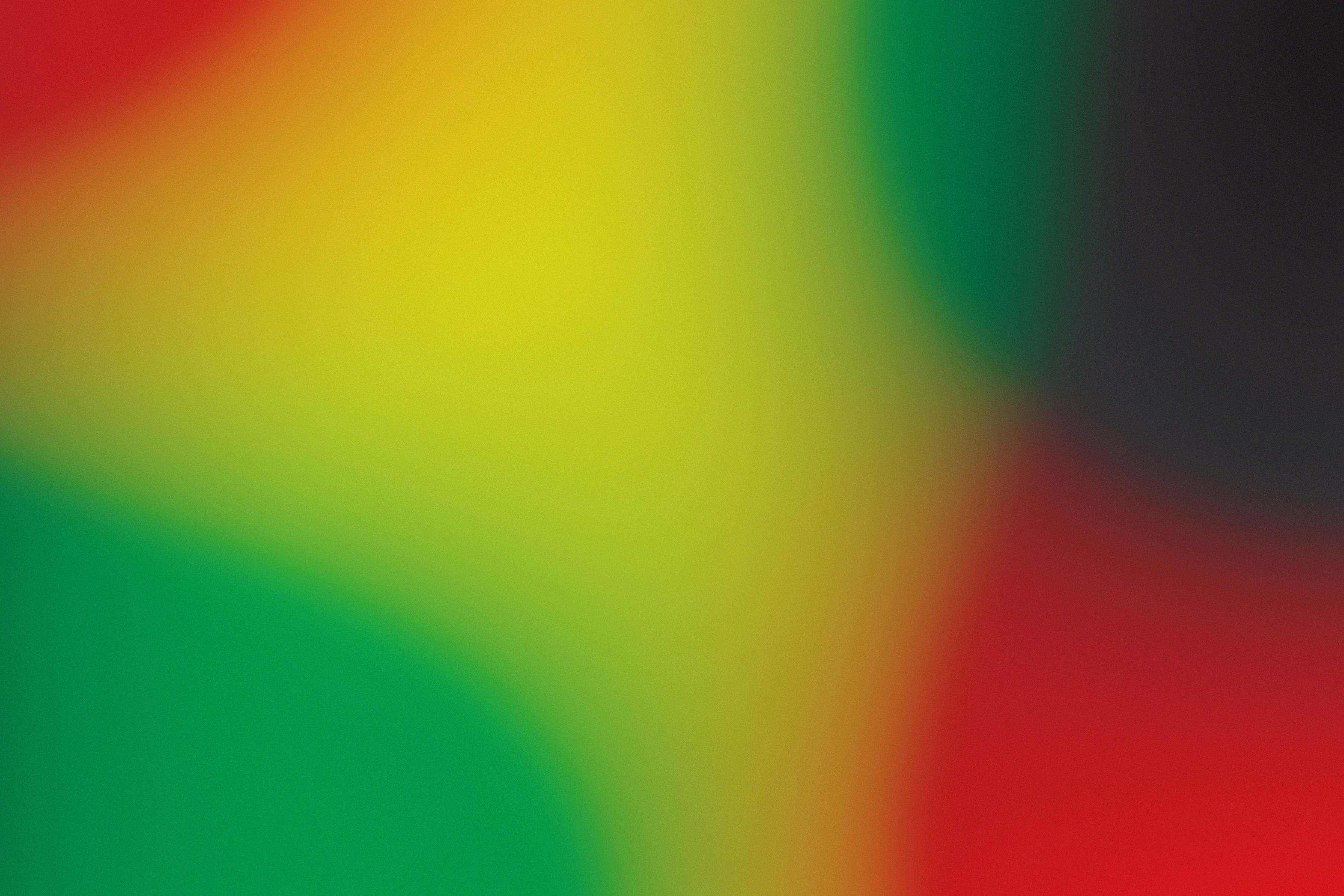 A soft abstract gradient of blurred red, yellow, green, and black colors