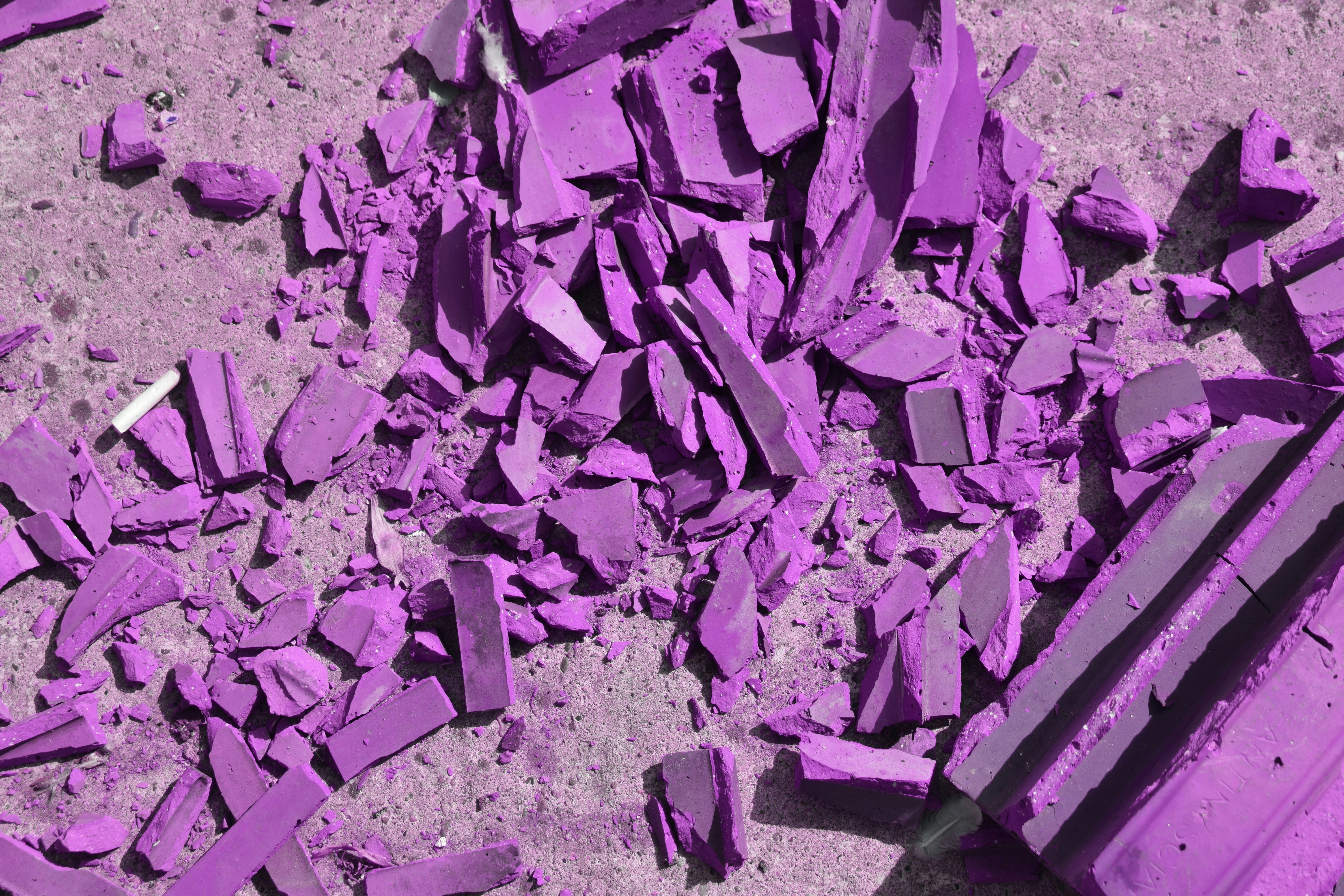 Shattered purple ceramic tiles scattered on a rough grey concrete surface