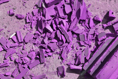 Shattered purple ceramic tiles scattered on a rough grey concrete surface